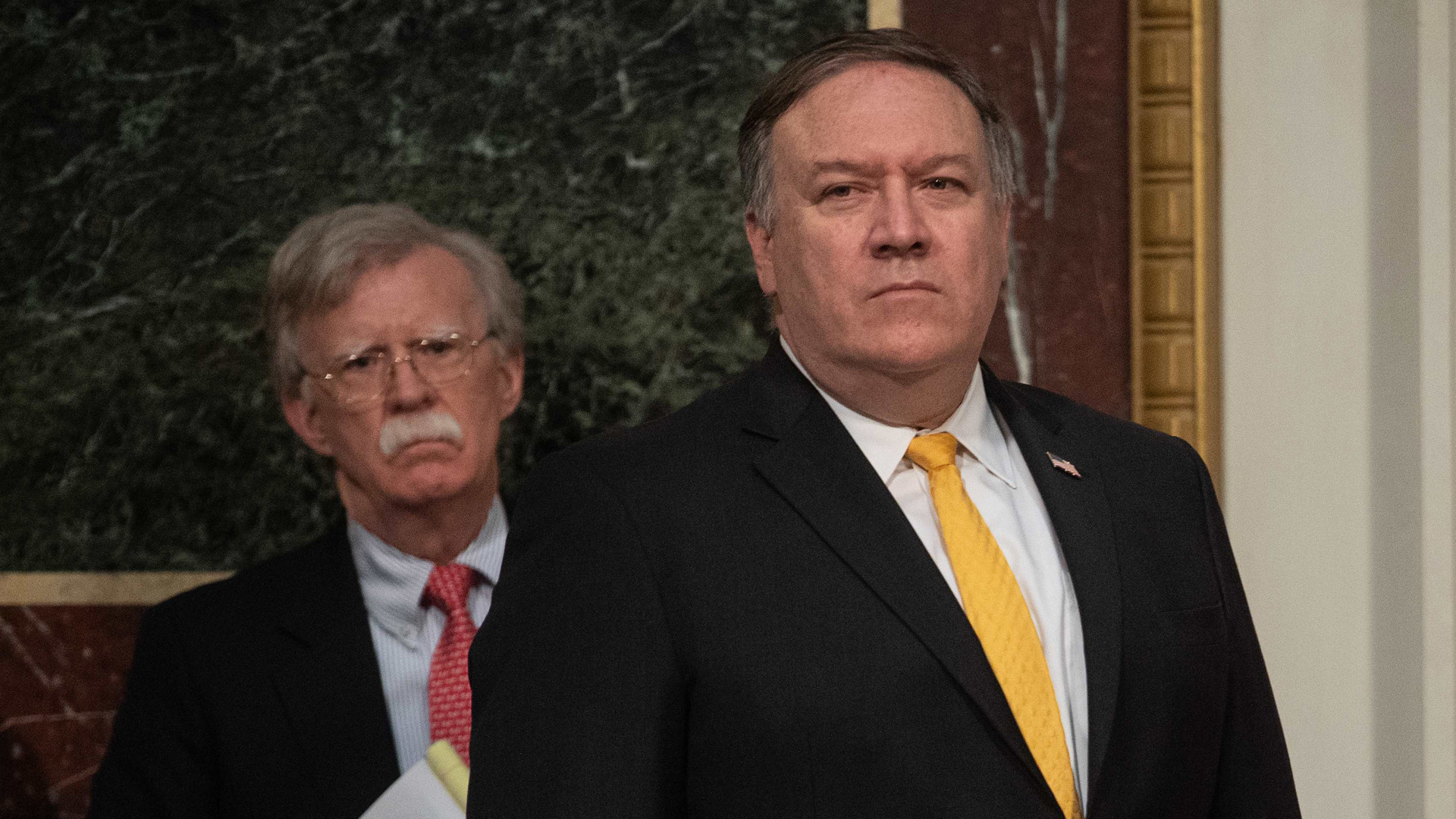 Secretary of State Mike Pompeo and National Security Adviser John Bolton listen to Donald Trump address the Interagency Task Force to Monitor and Combat Trafficking in Persons annual meeting at the White House in Washington, DC, on October 11, 2018. (Credit: NICHOLAS KAMM/AFP/Getty Images)