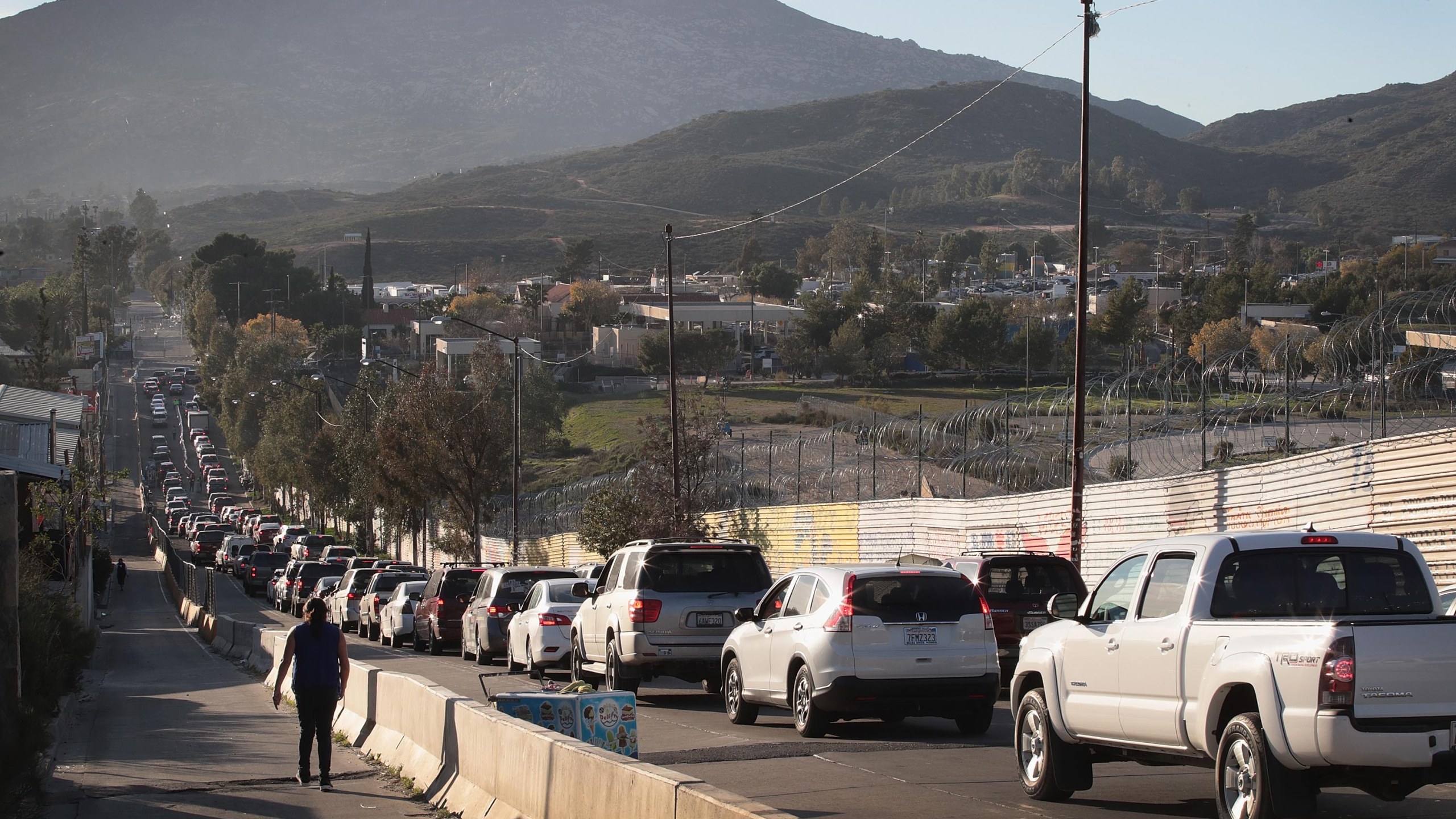 Motorists heading to the United States from Tecate, Mexico, wait along the U.S. border wall to pass through the port of entry on Jan. 27, 2019. (Credit: Scott Olson / Getty Images)