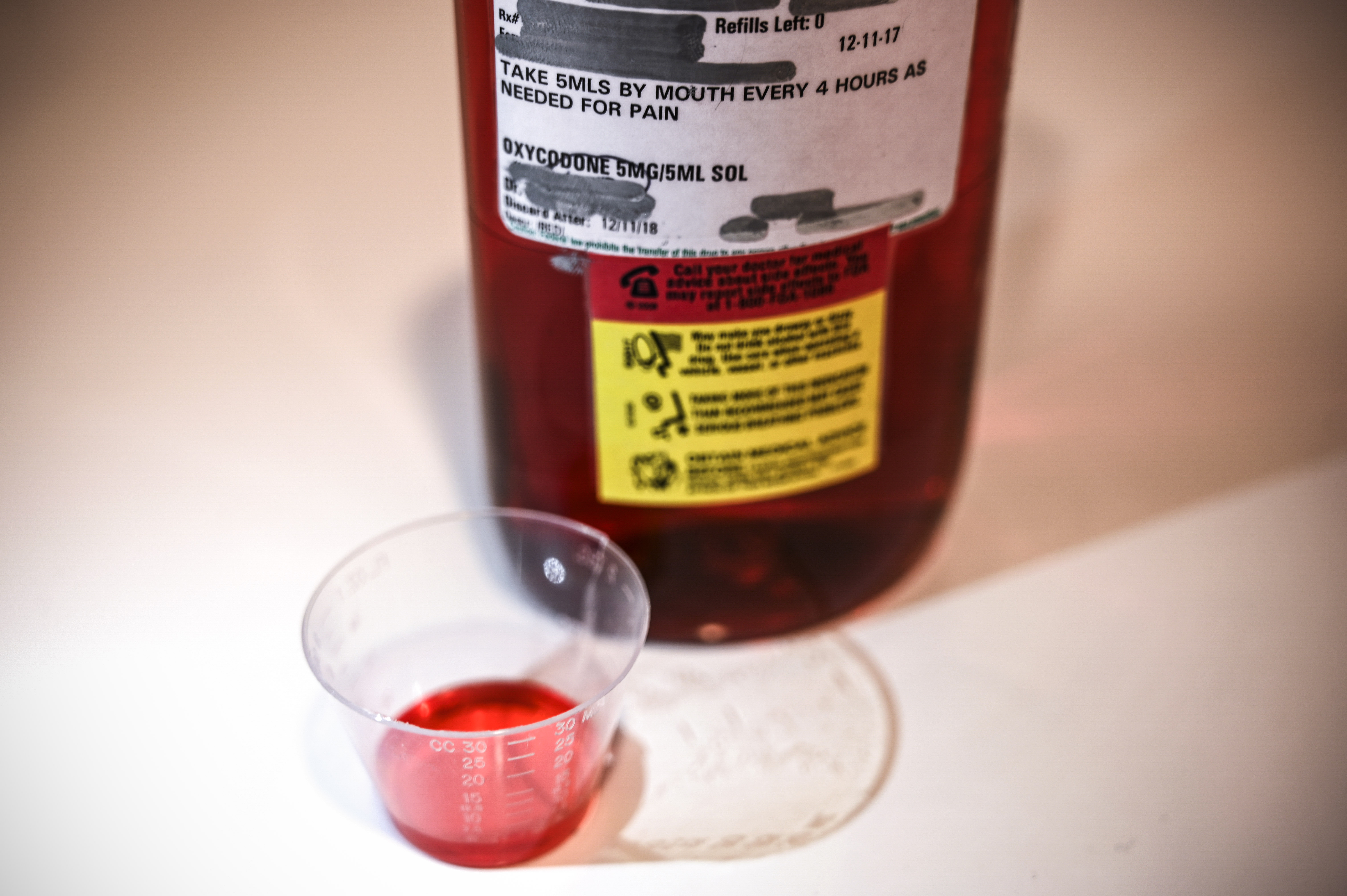 A 500ml bottle of liquid oxycodone, an opioid pain relief medication, and a dose of 5ml of the solution sit on a table in Washington, D.C., March 29, 2019. (Credit: EVA HAMBACH/AFP/Getty Images)