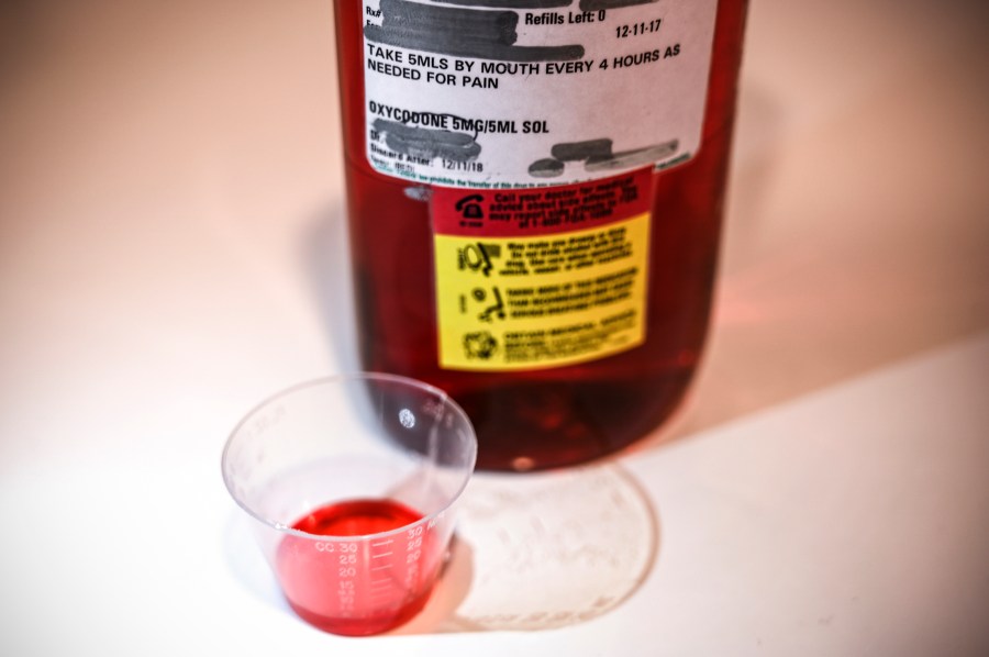 A 500ml bottle of liquid oxycodone, an opioid pain relief medication, and a dose of 5ml of the solution sit on a table in Washington, D.C., March 29, 2019. (Credit: EVA HAMBACH/AFP/Getty Images)