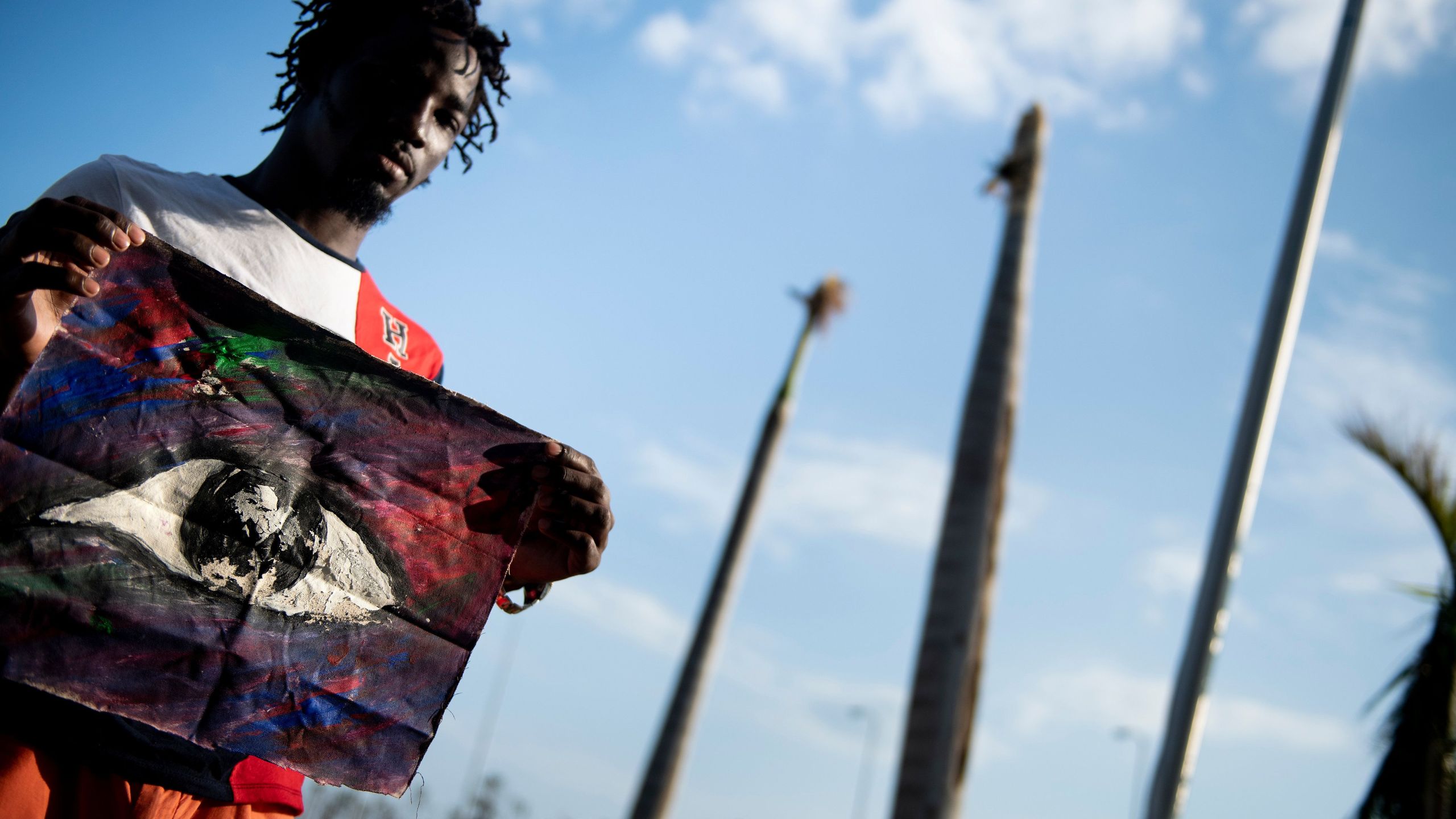 Shaquille Joseph poses with a painting that he made of the eye of Hurricane Dorian while waiting at Marsh Harbor International Airport for evacuation after Hurricane Dorian Sept. 7, 2019, in Marsh Harbor, Great Abaco. - He made the painting of the eye because he was able to escape flood waters and get to his roof during the stillness of the hurricane's eye. Bahamians who lost everything in the devastating passage of Hurricane Dorian were scrambling that same day to escape the worst-hit islands by sea or by air, after the historically powerful storm left at least 43 people dead with officials fearing a "significantly" higher toll. (Credit: BRENDAN SMIALOWSKI/AFP/Getty Images)