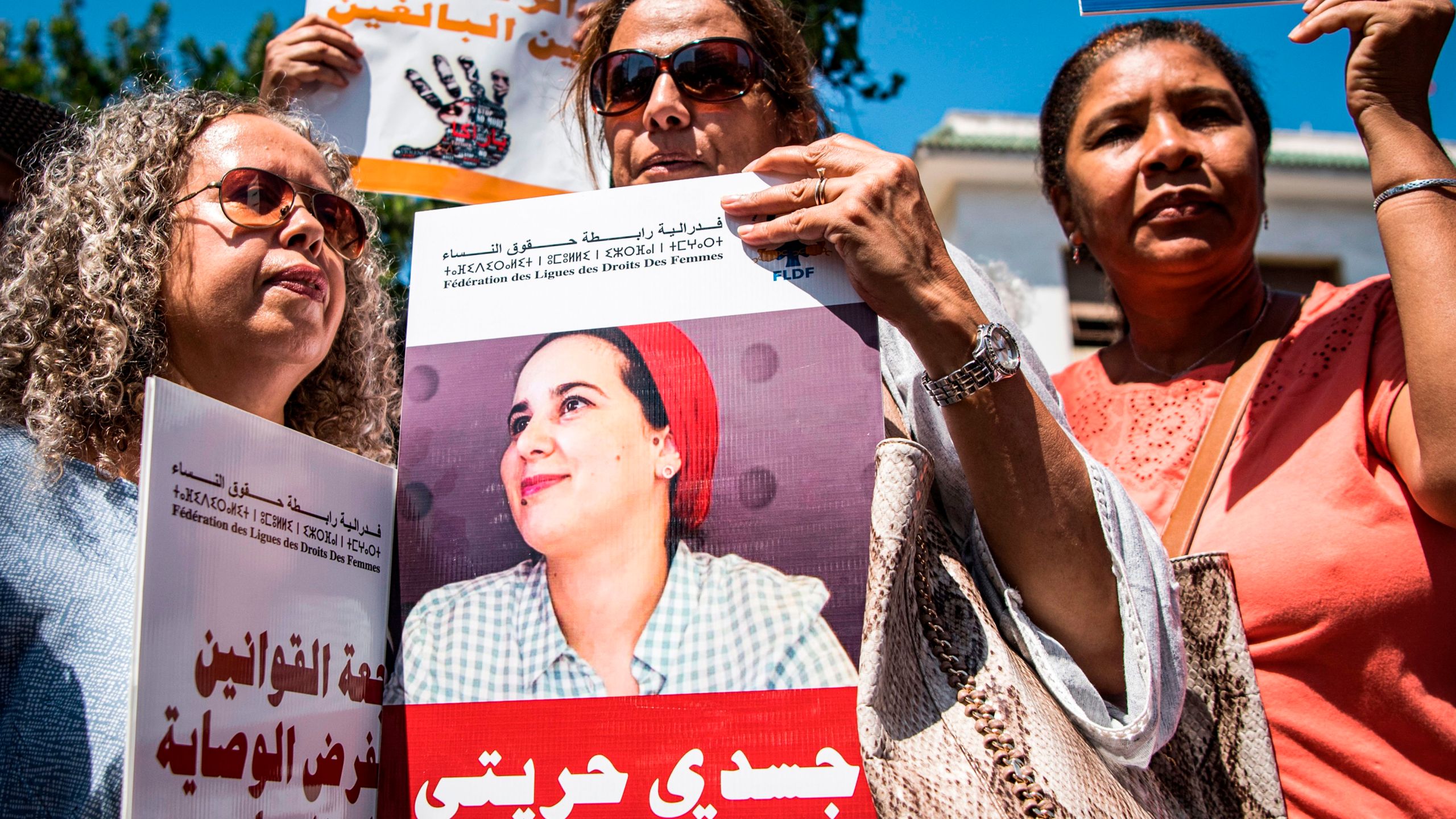 Demonstrators hold up a sign showing the portrait of Hajar Raissouni, a Morrocan journalist of the daily newspaper Akhbar El-Youm, with a caption below in Arabic reading "My body, My freedom", as they gather outside a courthouse holding her trial on charges of abortion in the capital Rabat on Sept. 9, 2019. (Credit: FADEL SENNA/AFP/Getty Images)