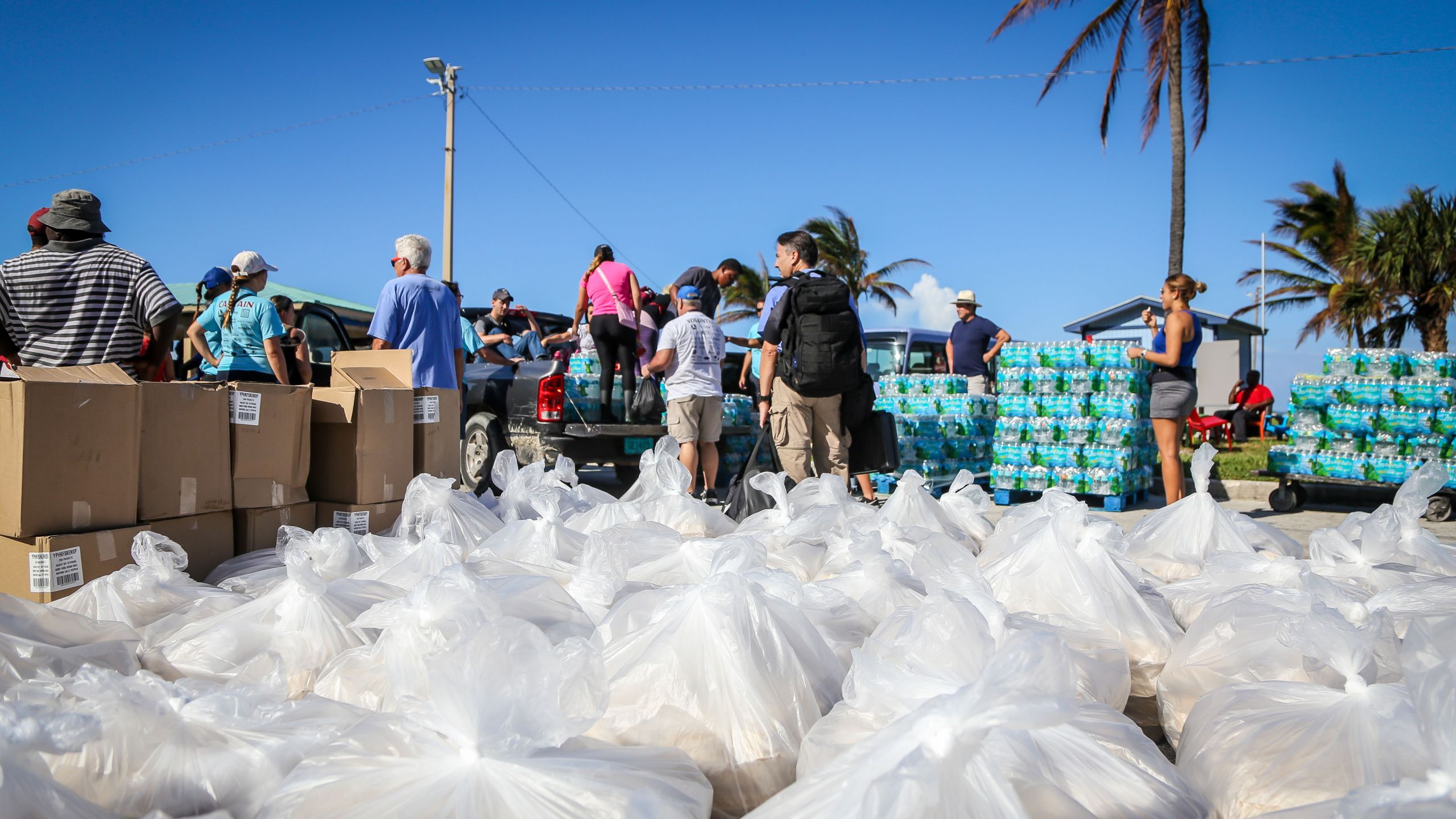 People from the Bahamas Relief Cruise, operated by the Bahamas Paradise Cruise Line, stand next to some 20,000 meals prepared for Bahamians to be delivered to distribution centers and homes in the aftermath of Hurricane Dorian and Tropical Storm Humberto in Freeport, Grand Bahama, Bahamas, on Sept. 17, 2019. (Credit: ZAK BENNETT/AFP/Getty Images)