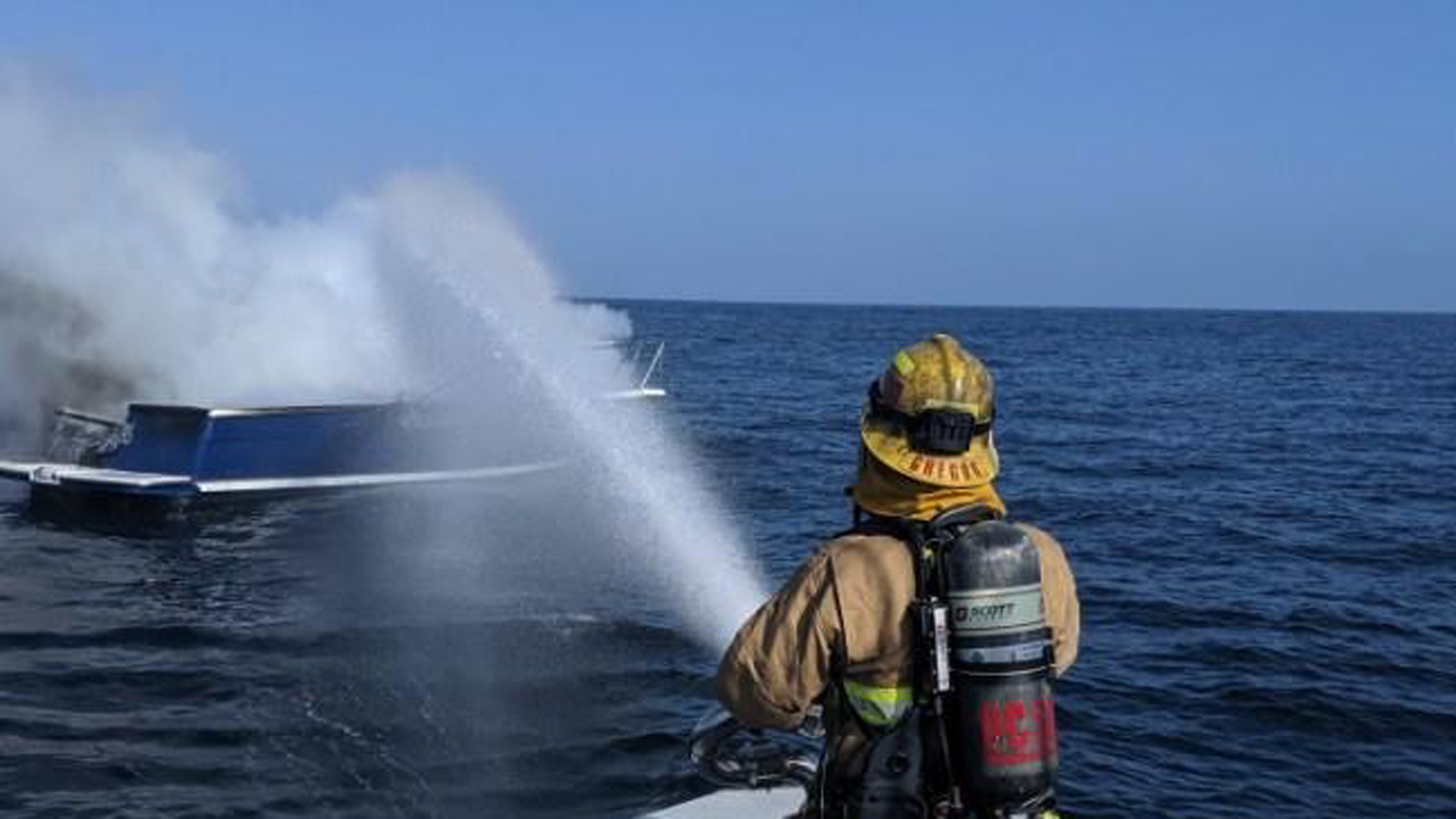 A Harbor Patrol first responder in Orange County hoses down a boat fire 10 miles off the Newport Coast on Oct. 18, 2019. (Credit: Orange County Sheriff's Department)