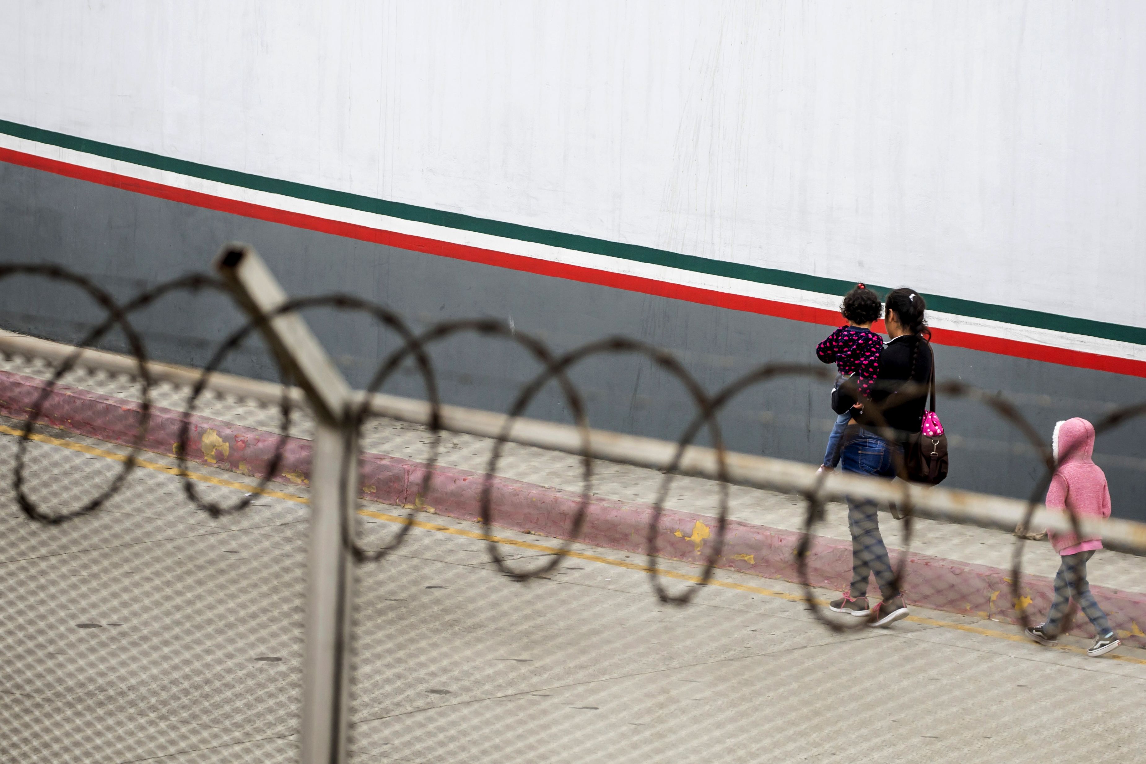 A Central American migrant and her children walk outside El Chaparral port of entry, in Tijuana, Mexico, on July 17, 2019. (Credit: Omar Martínez / AFP / Getty Images)