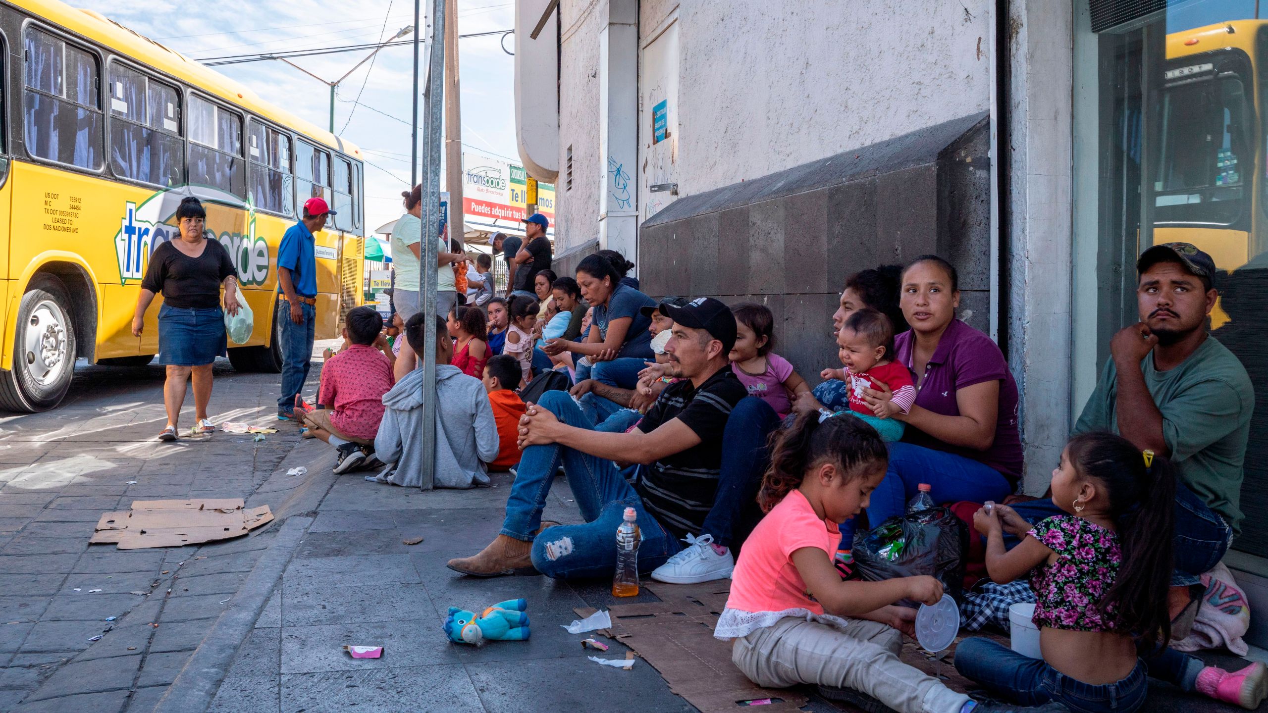 Migrants, mostly from Mexico, sit on the ground as they wait near the Paso del Norte Bridge at the Mexico-U.S. border in Ciudad Juarez, Mexico, on Sept. 12, 2019. (Credit: Paul Ratje / AFP / Getty Images)