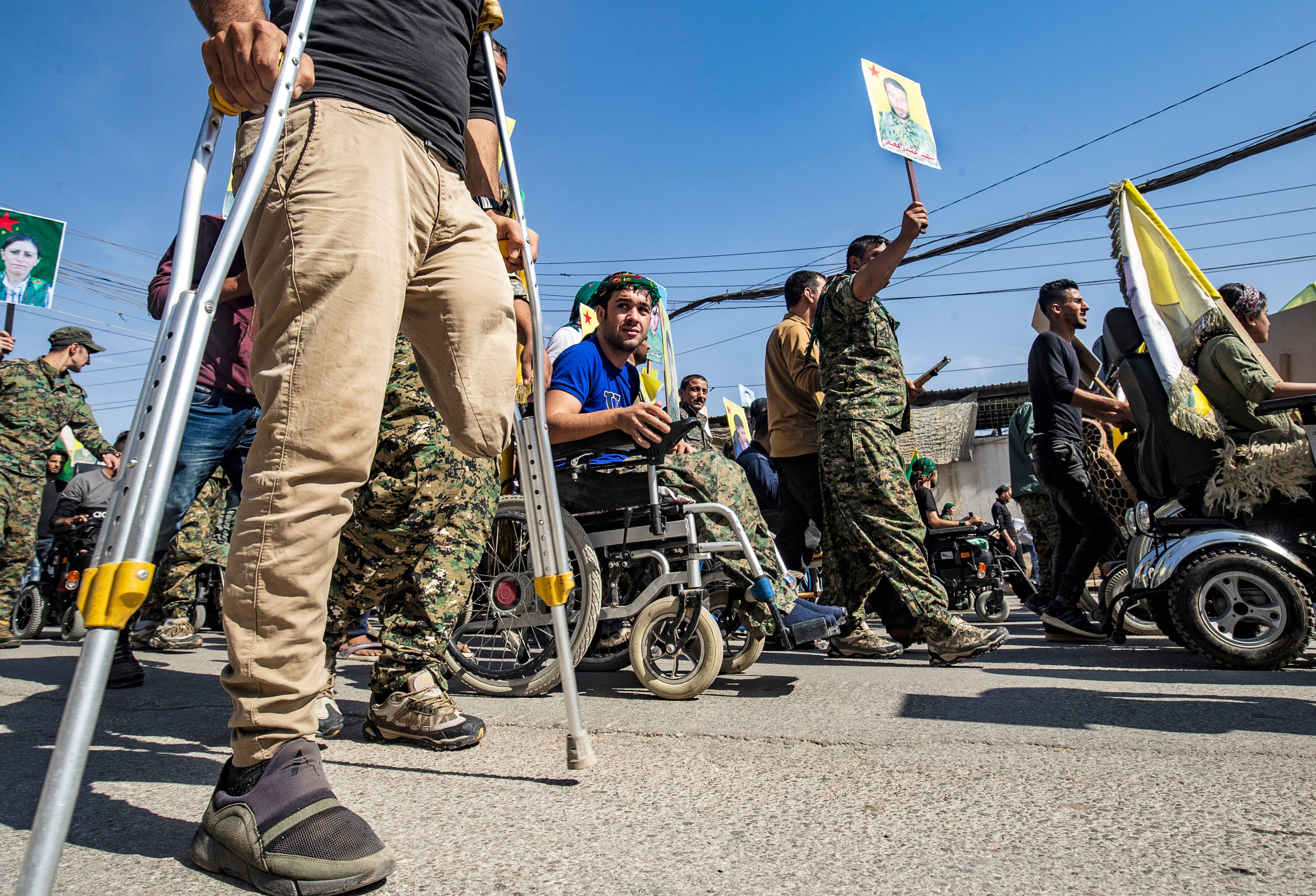 Fighters and veterans from the Kurdish women's protection units (YPJ) and the people's protection units (YPG) march in front of the United Nations headquarters in the northern Kurdish Syrian city of Qamishli during a protest against Turkish threats in the Kurdish region, on Oct. 8, 2019. (Credit: DELIL SOULEIMAN/AFP via Getty Images)