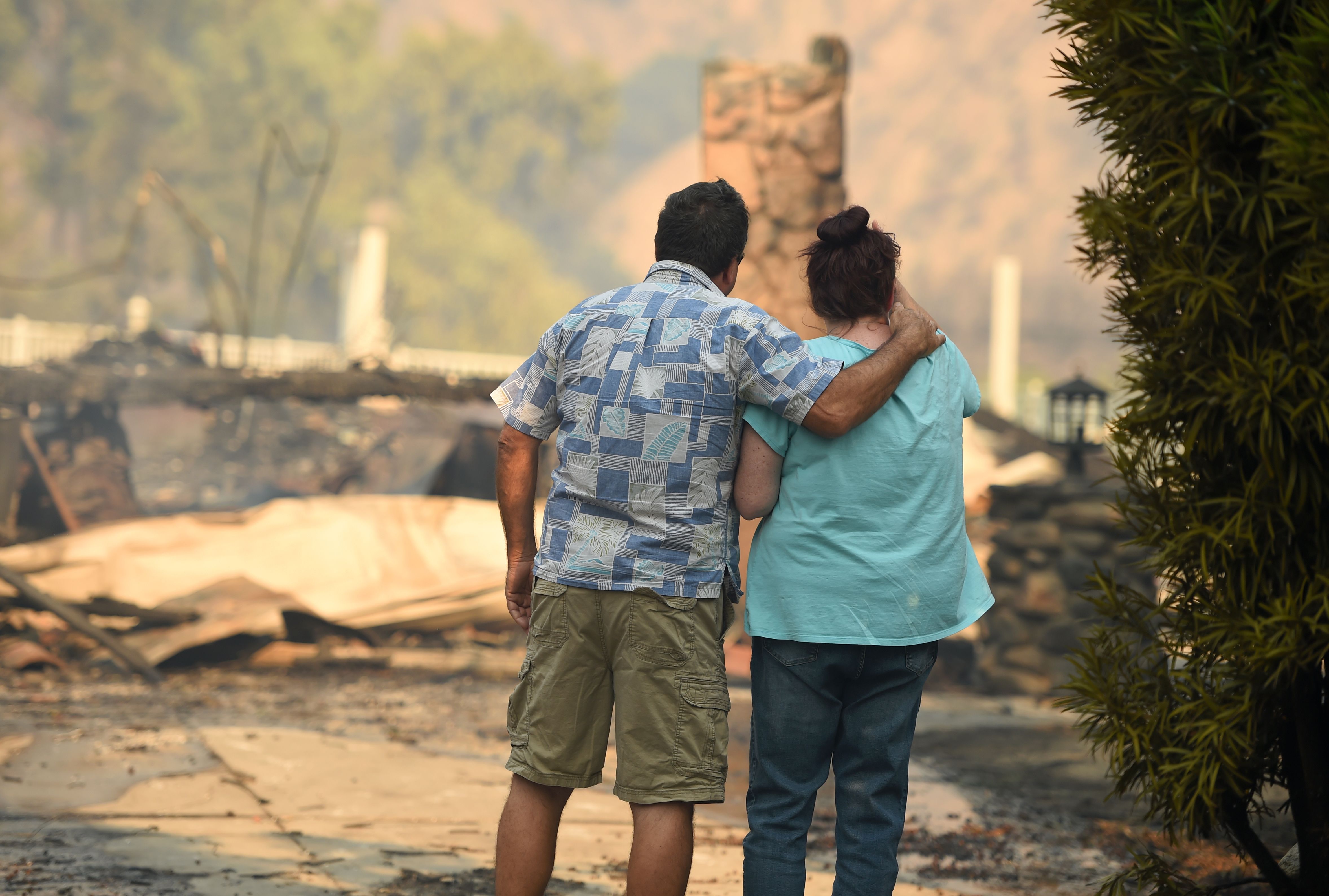 Eyad Jarjour, left, consoles his neighbor as she views her burned home after flames from the Saddleridge Fire tore through Granada Hills on Oct. 11, 2019. (Credit: Josh Edelson / AFP / Getty Images)