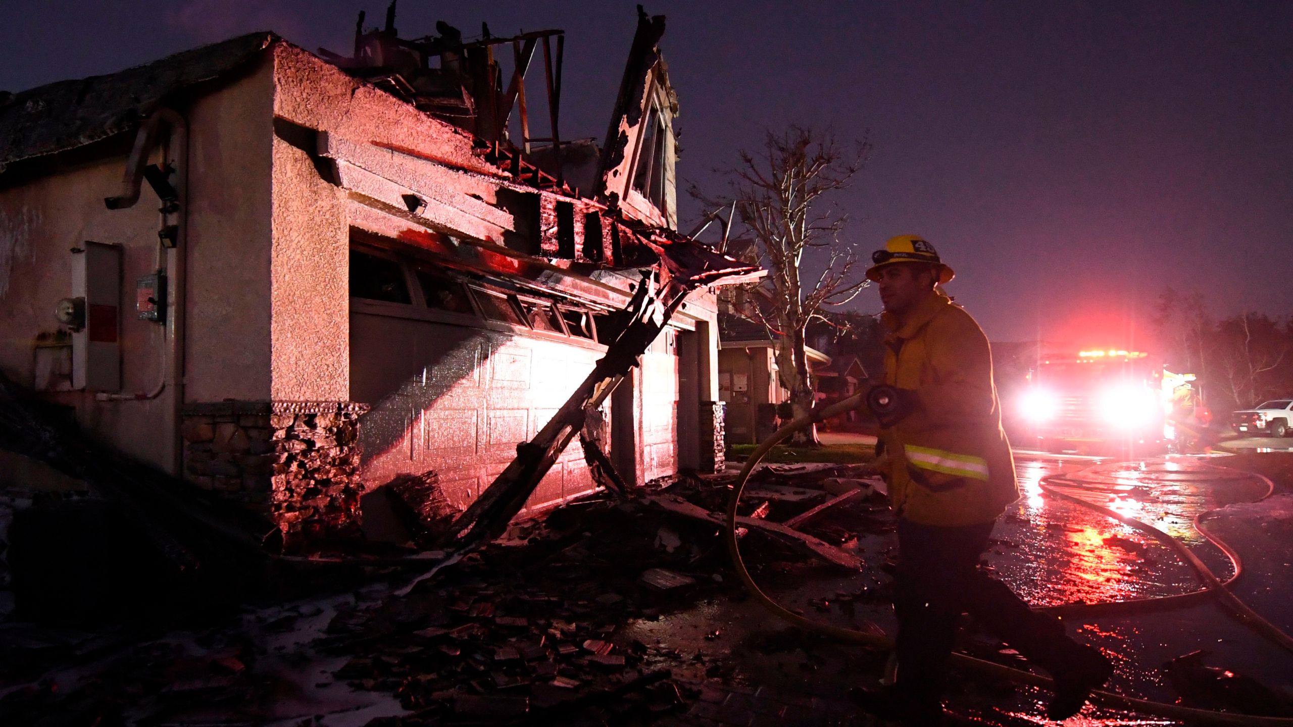 Firefighters hose down a burning house during the Tick Fire in Agua Dulce near Santa Clarita, Calif., on Oct. 25, 2019. (Credit: MARK RALSTON/AFP via Getty Images)