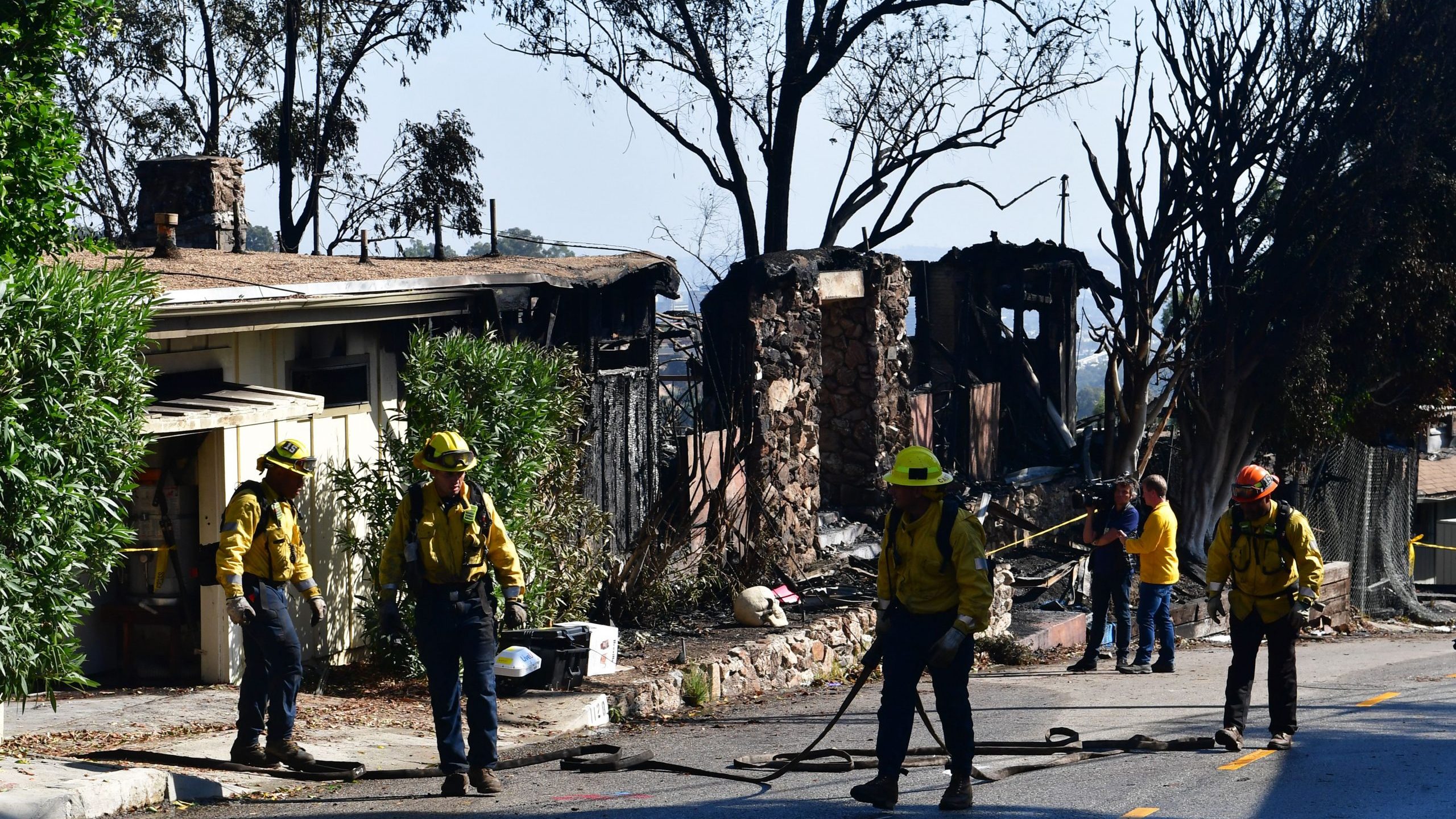 Firefighters gather their hoses near destroyed homes along North Tigertail Road during the Getty Fire on Oct. 29, 2019. (Credit: FREDERIC J. BROWN/AFP via Getty Images)