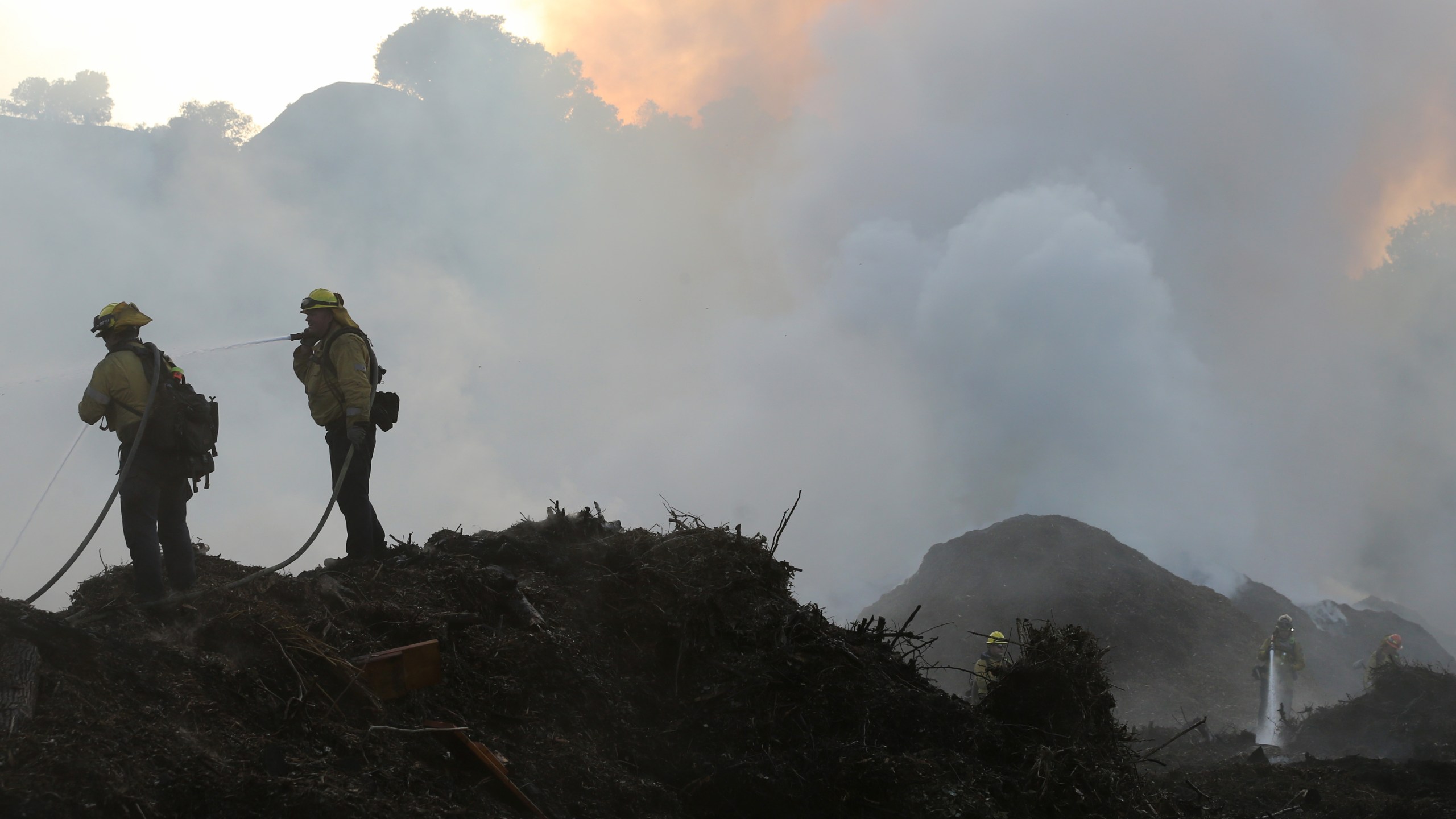 Firefighters work on containing a flare up at a mulch supplier in Sylmar during the Saddleridge Fire on Oct. 12, 2019. (Credit: Mario Tama / Getty Images)