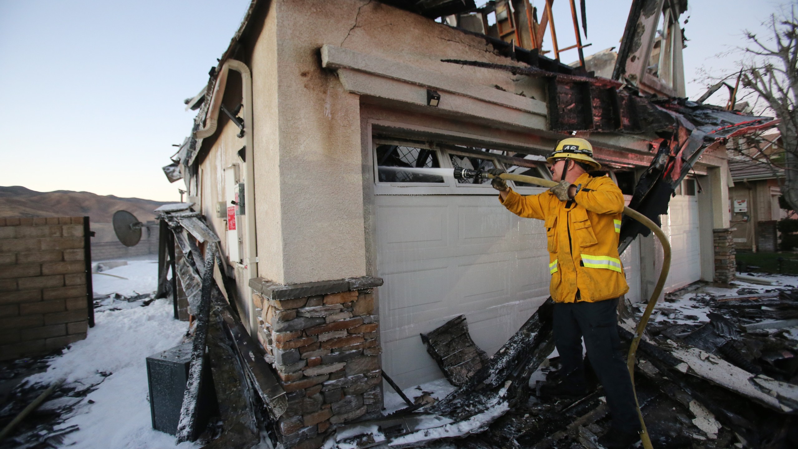 A firefighter works to put out a house fire caused by the Tick Fire on Oct. 25, 2019, in Canyon Country, Calif. (Credit: Mario Tama/Getty Images)