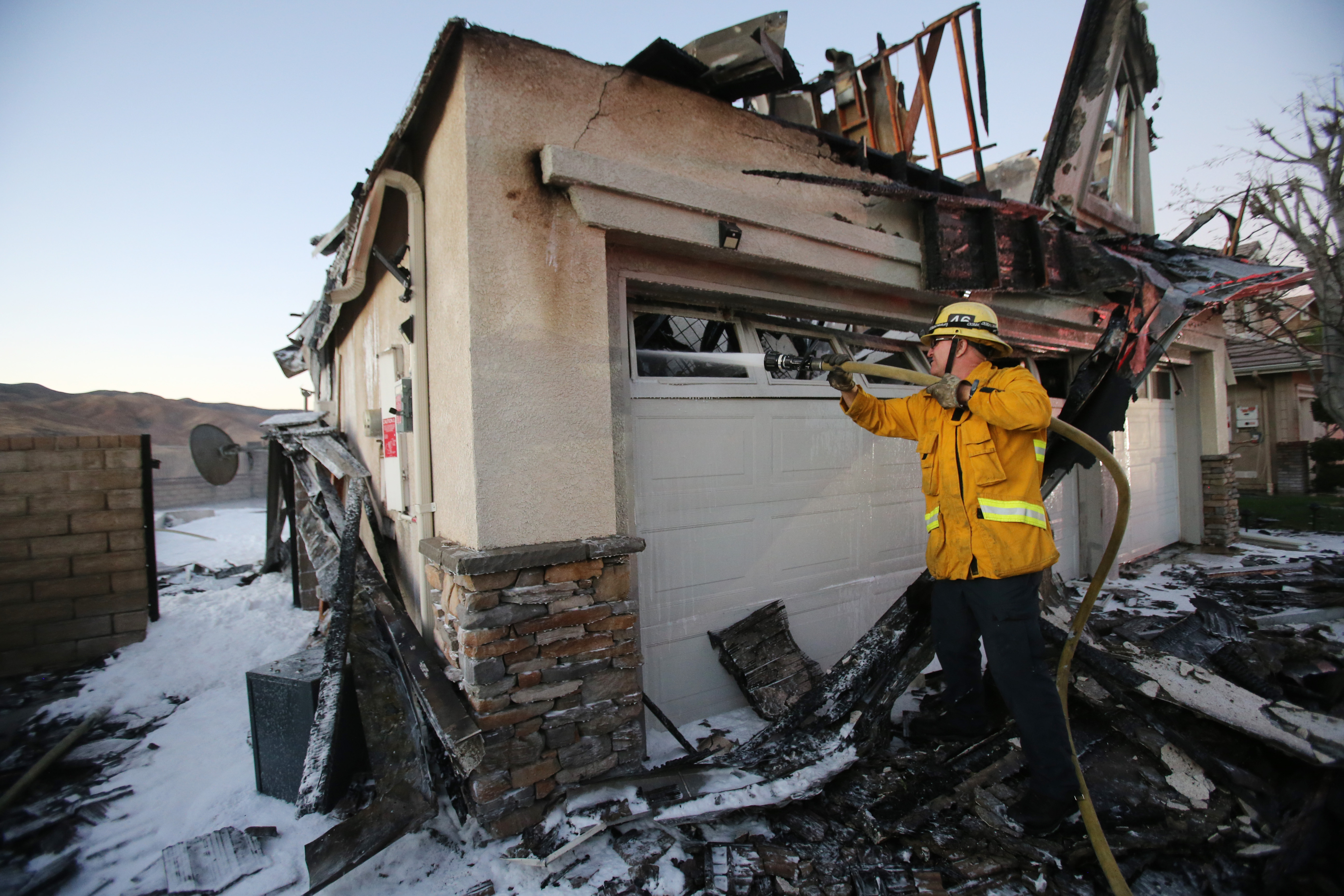 A firefighter works to put out a house fire caused by the Tick Fire on Oct. 25, 2019, in Canyon Country, Calif. (Credit: Mario Tama/Getty Images)