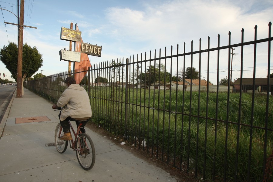 A man bicycles past a lot in Compton vacated years ago when a long-established business failed, on March 3, 2009. (Credit: David McNew / Getty Images)