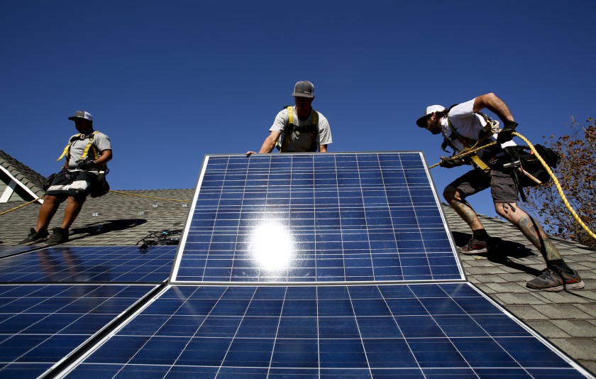 A crew installs rooftop solar panels at a home in Camarillo in 2013. (Credit: Anne Cusack / Los Angeles Times)