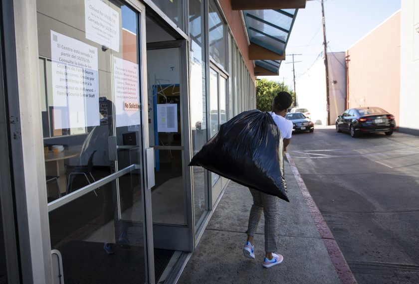 A staffer carries a trash bag full of belongings out of the offices of the Youth Policy Institute on Oct. 25, 2019, the day the nonprofit abruptly closed. (Credit: Francine Orr / Los Angeles Times)