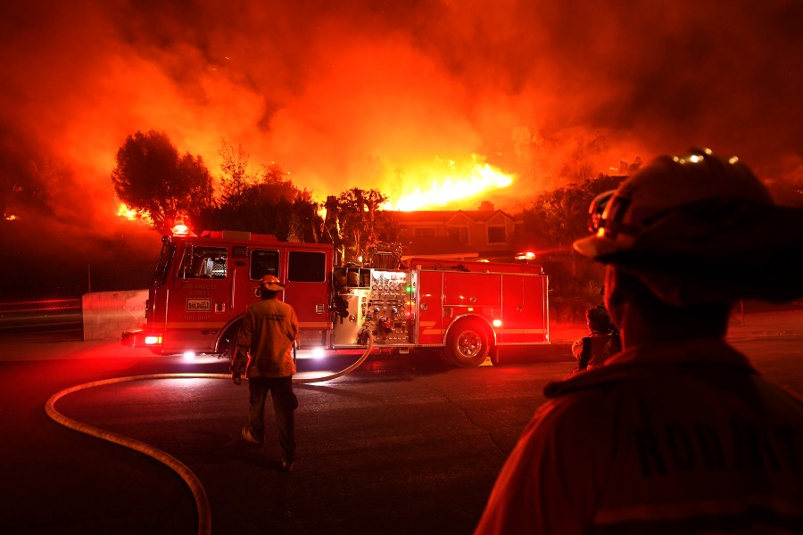 Los Angeles County firefighters look on as the Woolsey Fire explodes behind a house in the West Hills neighborhood on Nov. 9, 2018, in Los Angeles, California. (Credit: Kevork Djansezian/Getty Images)