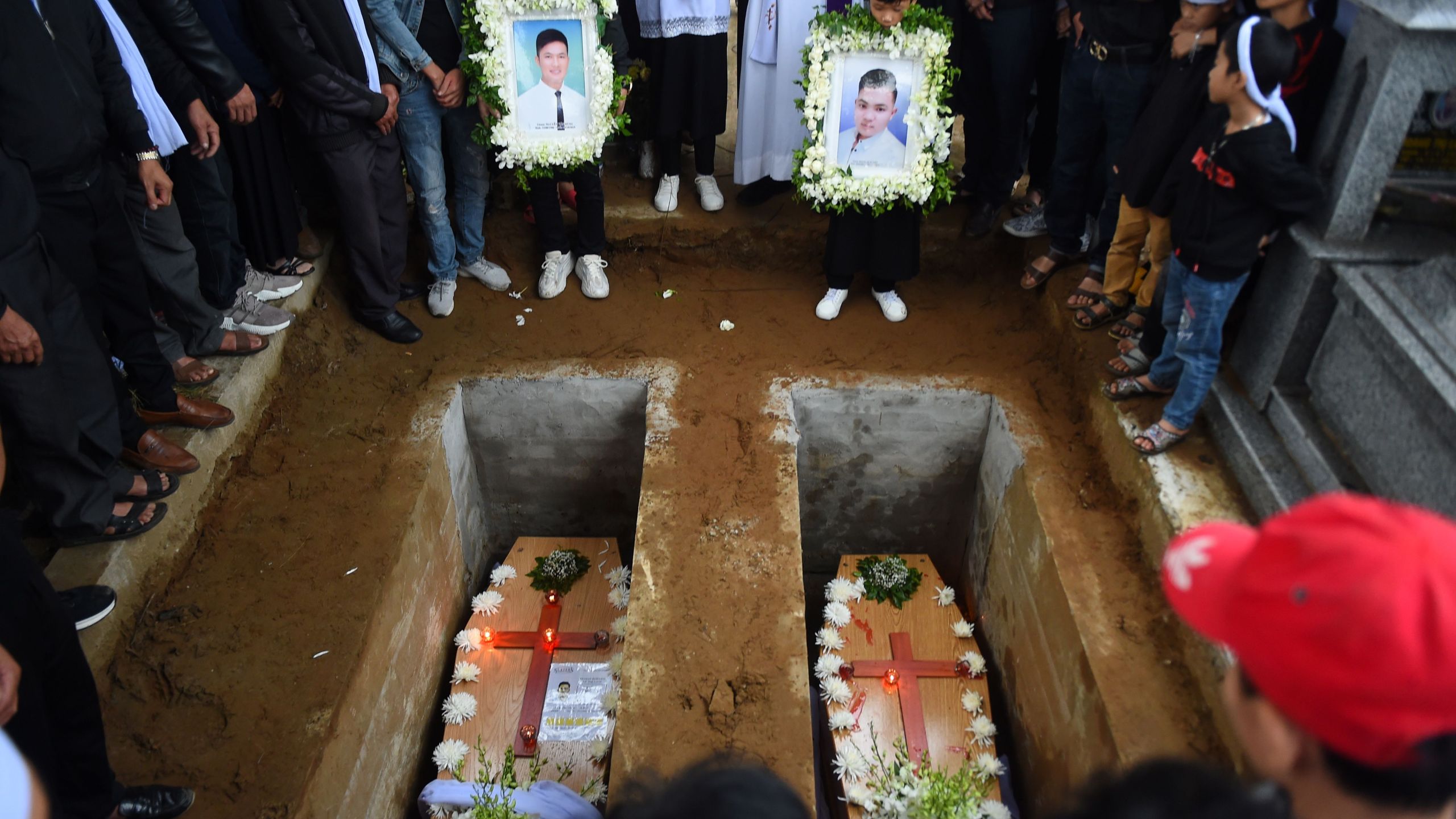 Family members pray during final rites at the burial of the remains Nguyen Van Hung (L) and Hoang Van Tiep (R) at a cemetery in Dien Chau district, Nghe An province on Nov. 28, 2019. (Credit: NHAC NGUYEN/AFP via Getty Images)