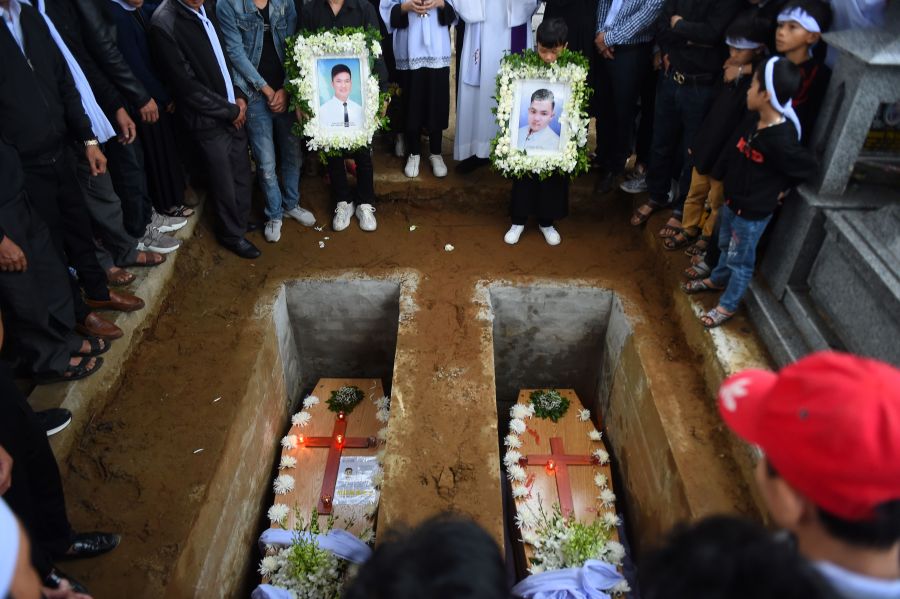 Family members pray during final rites at the burial of the remains Nguyen Van Hung (L) and Hoang Van Tiep (R) at a cemetery in Dien Chau district, Nghe An province on Nov. 28, 2019. (Credit: NHAC NGUYEN/AFP via Getty Images)