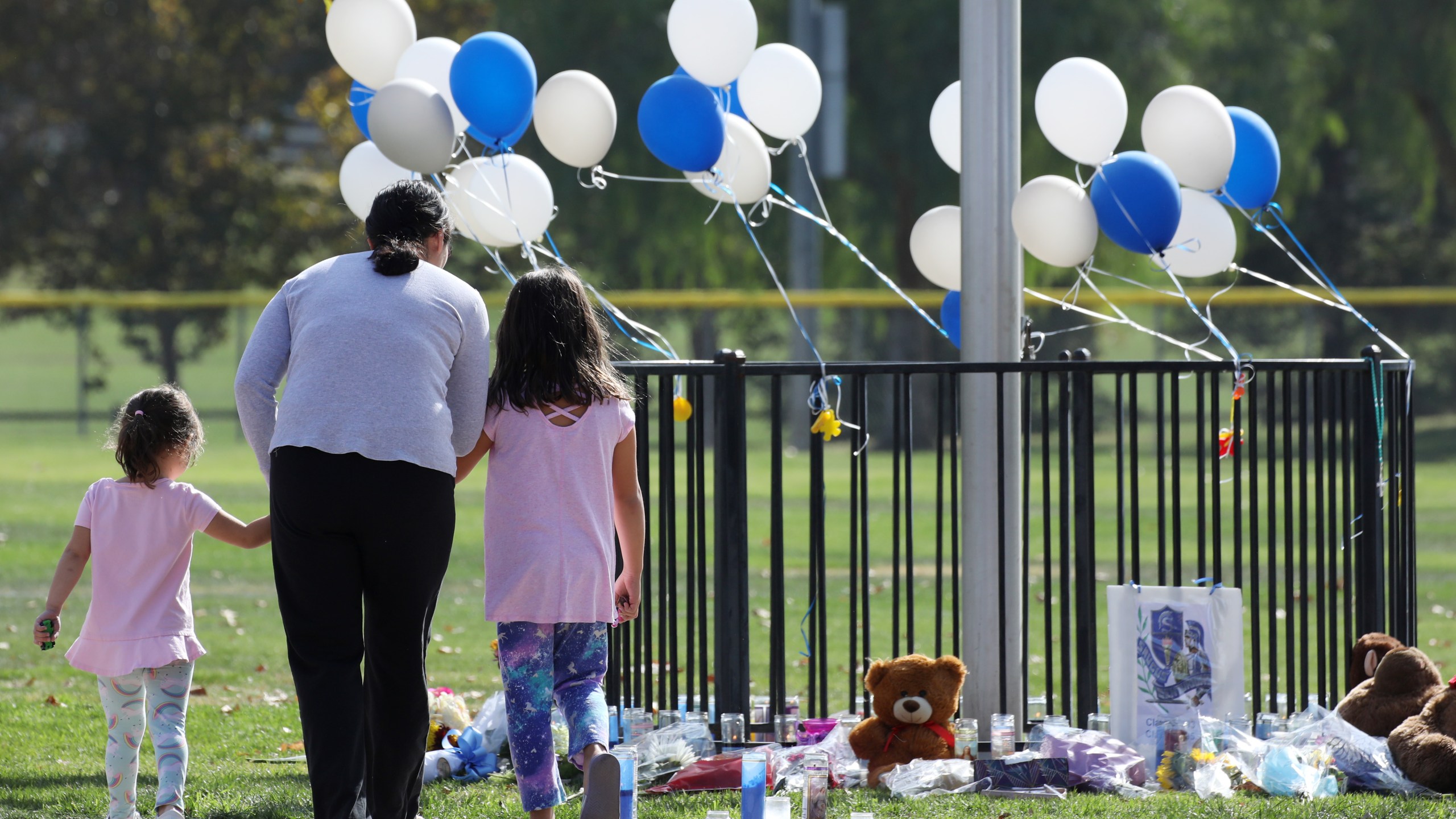 A woman and two girls visit a makeshift memorial in Central Park for victims of the shooting at nearby Saugus High School on Nov. 15, 2019 in Santa Clarita. (Credit: Mario Tama/Getty Images)