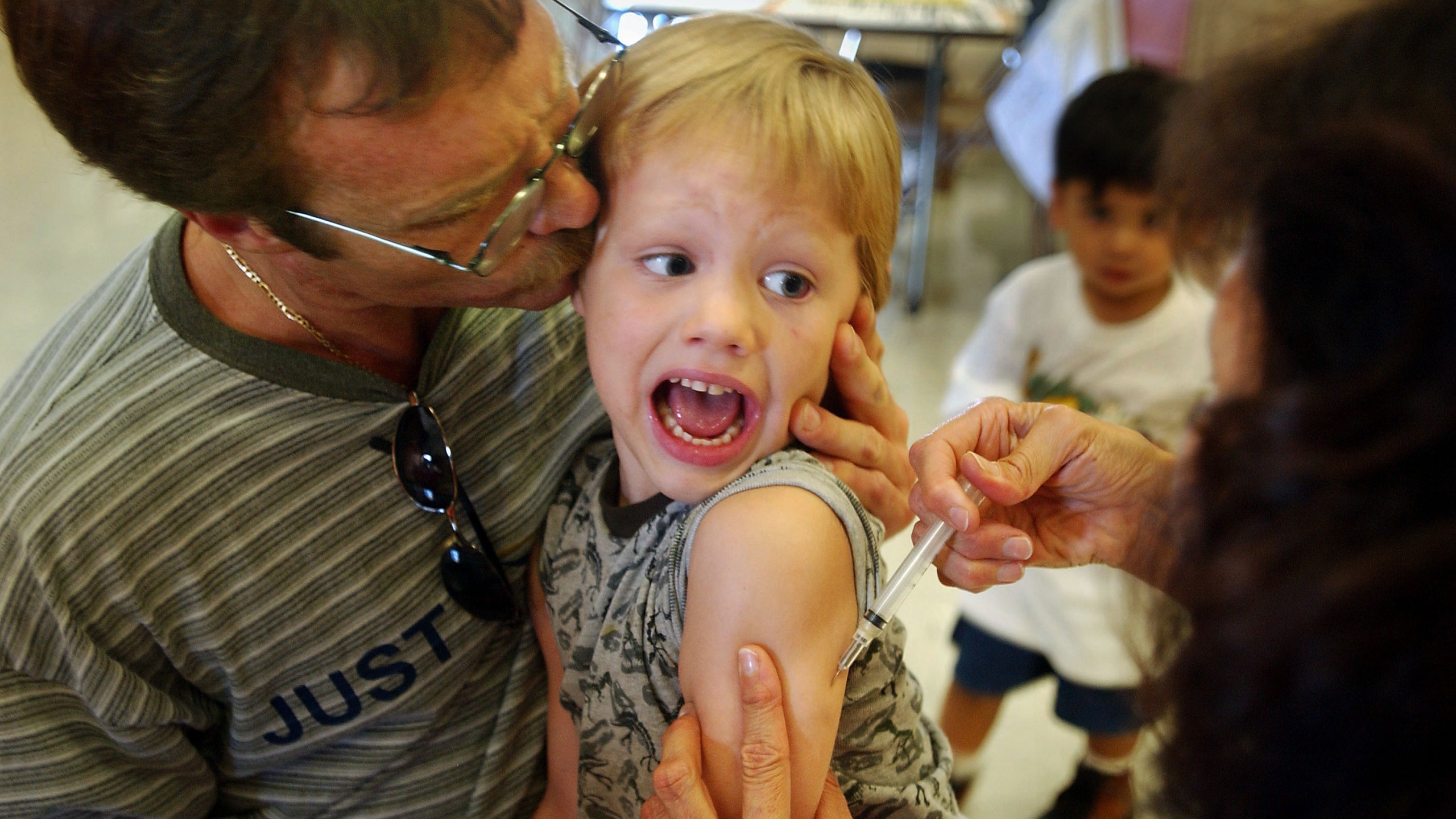 Incoming kindergartener Jeremy Conner, 5, reacts to a Measles, Mumps and Rubella vaccination (MMR) as his father Mark Conner tries to comfort him Aug. 26, 2002, in Santa Ana, Calif. (Credit: David McNew/Getty Images)