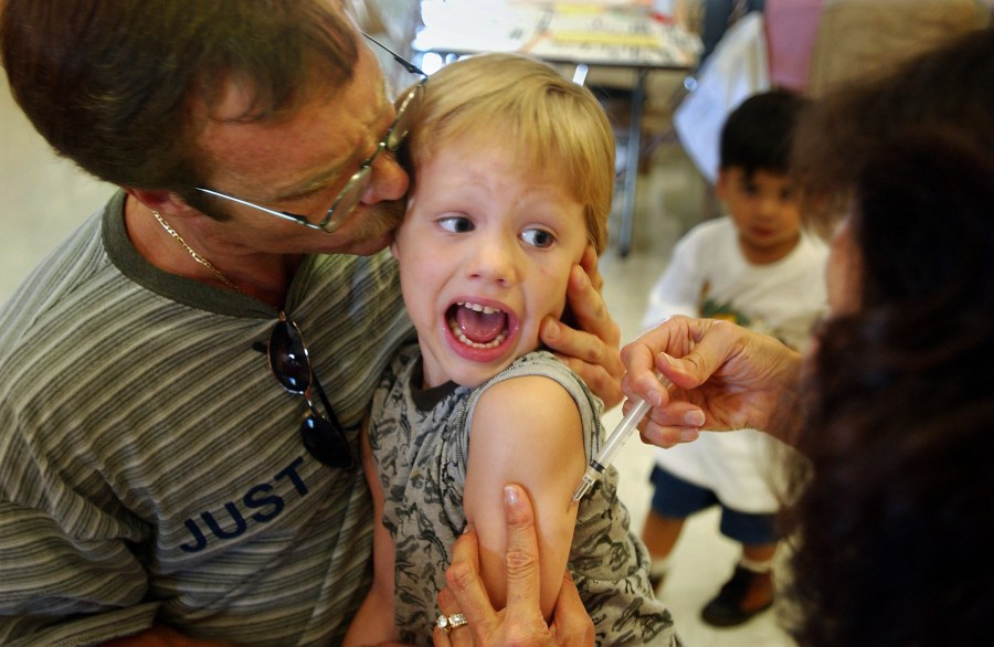 Incoming kindergartener Jeremy Conner, 5, reacts to a Measles, Mumps and Rubella vaccination (MMR) as his father Mark Conner tries to comfort him Aug. 26, 2002, in Santa Ana, Calif. (Credit: David McNew/Getty Images)