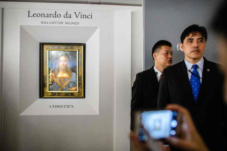 This picture taken on October 13, 2017, shows a man identified by local Hong Kong media as former CIA agent Jerry Chun Shing Lee standing in front of a member of security at the unveiling of Leonardo da Vinci's 'Salvator Mundi' painting at the Christie's showroom in Hong Kong. (Credit: Anthony Wallace/AFP via Getty Images)