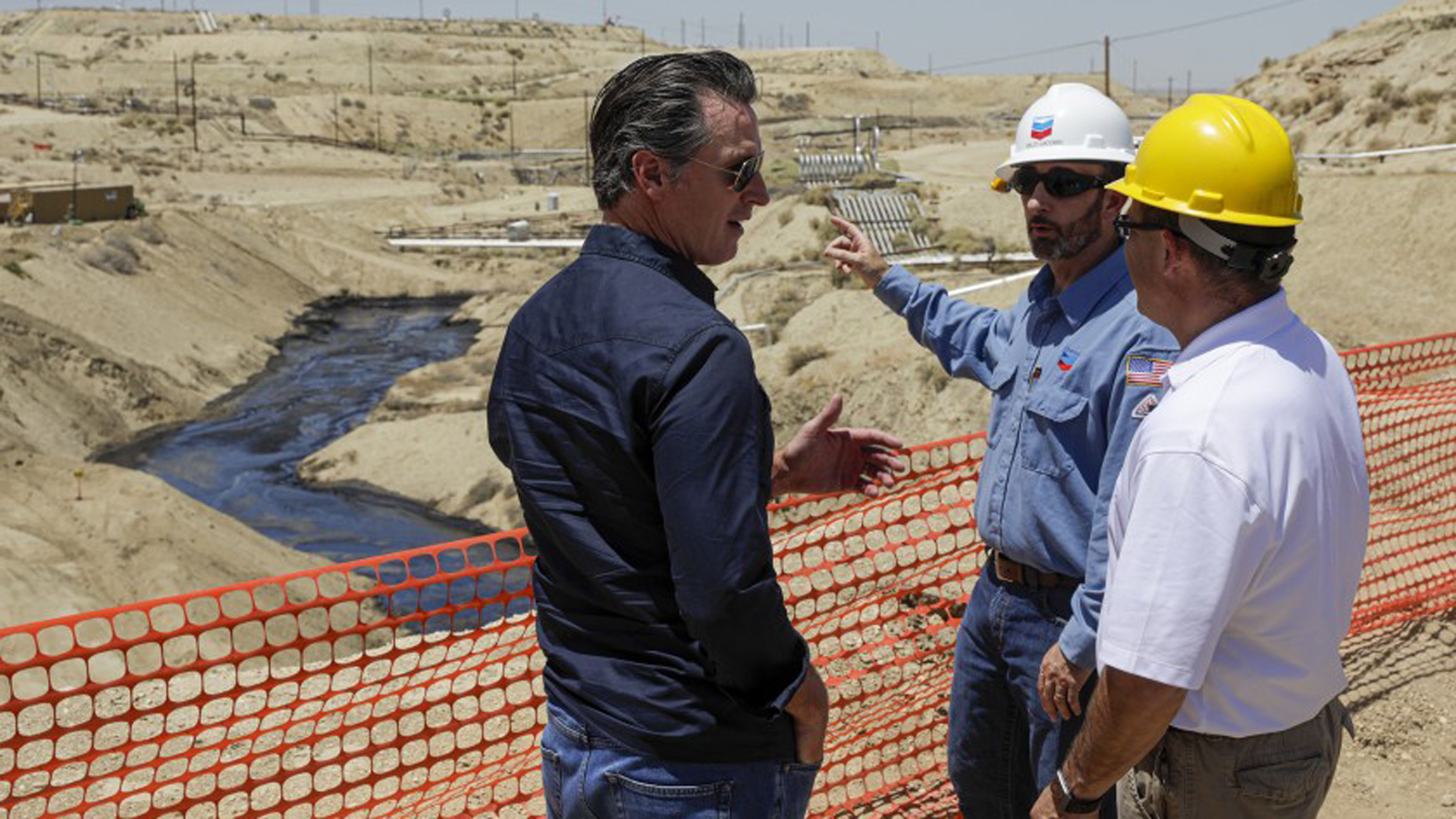 Gov. Gavin Newsom, left, is briefed by Billy Lacobie, of Chevron, center, and Jason Marshall of California department of conservation division of oil, gas, in July while touring the Chevron oil field west of Bakersfield where a spill of more than 800,000 gallons flowed into a dry creek bed. (Credit: Irfan Khan/Los Angeles Times)