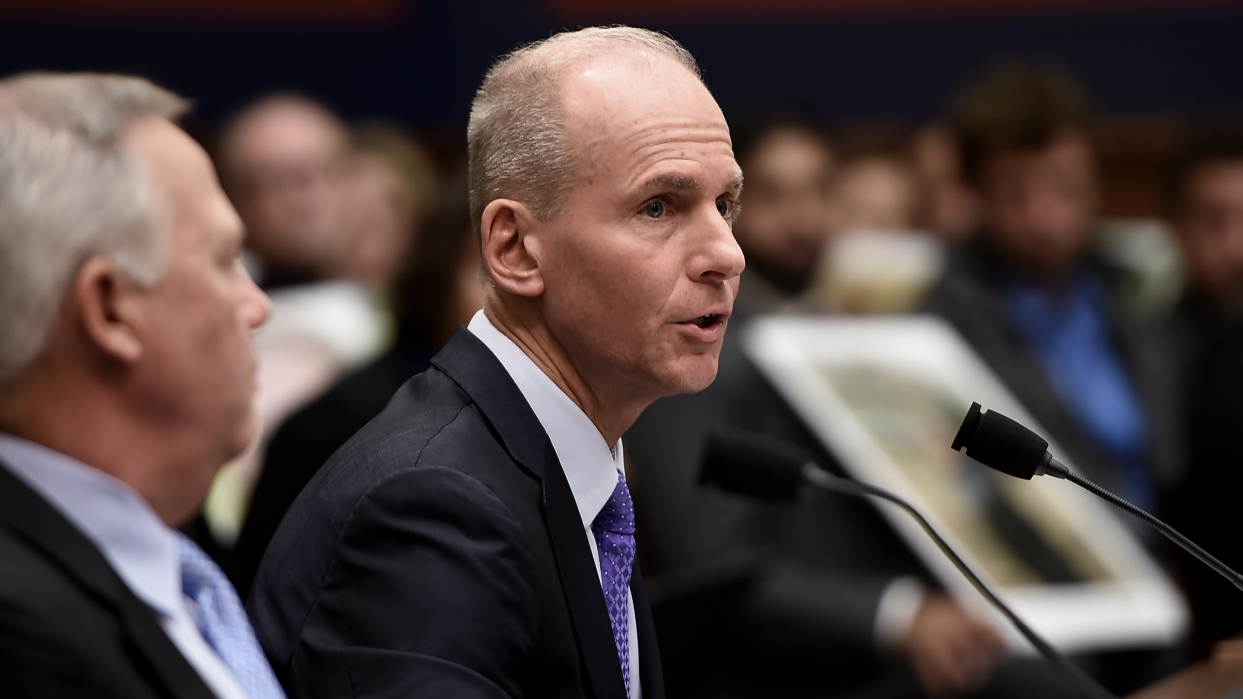 Family members of those who died aboard Ethiopian Airlines Flight 302 hold photographs of their loved ones as Dennis Muilenburg, right, testifies at a hearing in front of congressional lawmakers on Capitol Hill in Washington, D.C. on Oct. 30, 2019. (Credit: OLIVIER DOULIERY/AFP via Getty Images)