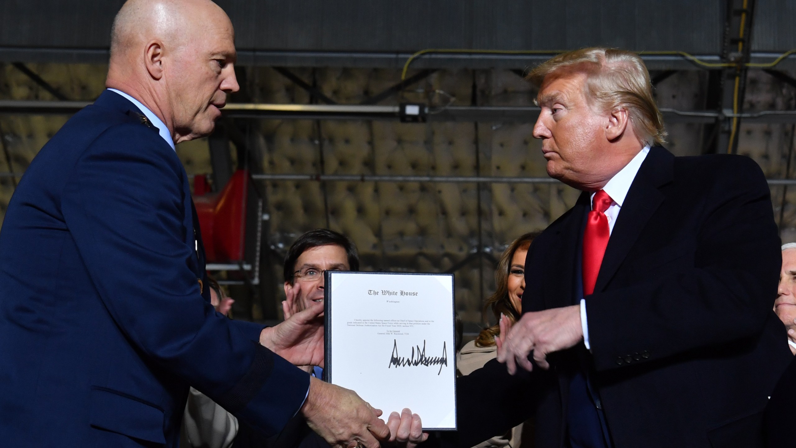 President Donald Trump, right, hands General John W. Raymond a document after signing the National Defense Authorization Act at Joint Base Andrews, Maryland, on Dec. 20, 2019. (Credit: Nicholas Kamm / AFP / Getty Images)