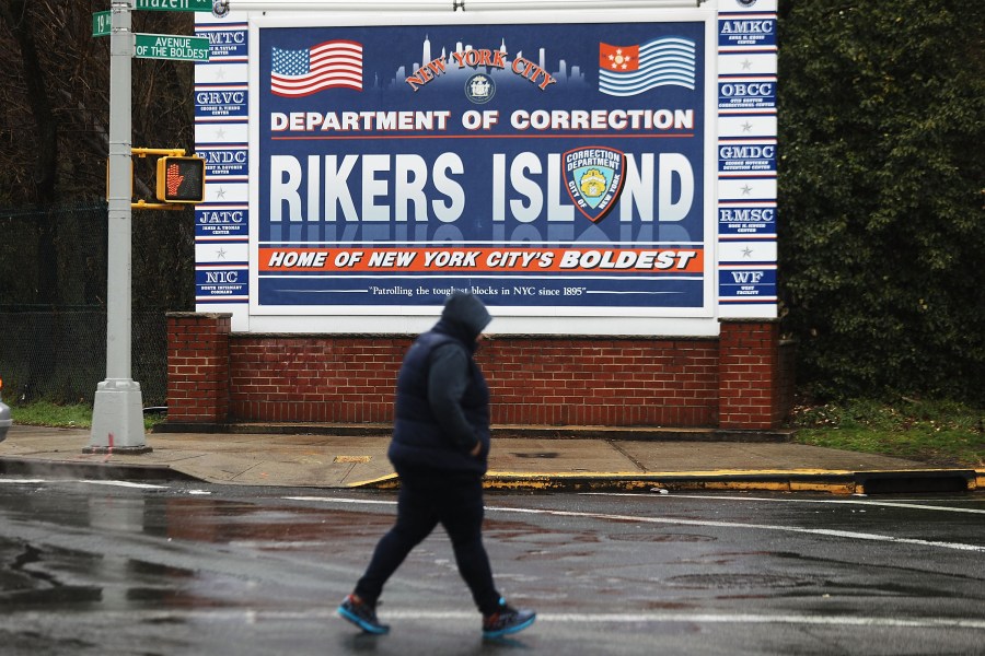 A woman walks by a sign at the entrance to Rikers Island on March 31, 2017 in New York City. (Credit: Spencer Platt/Getty Images)