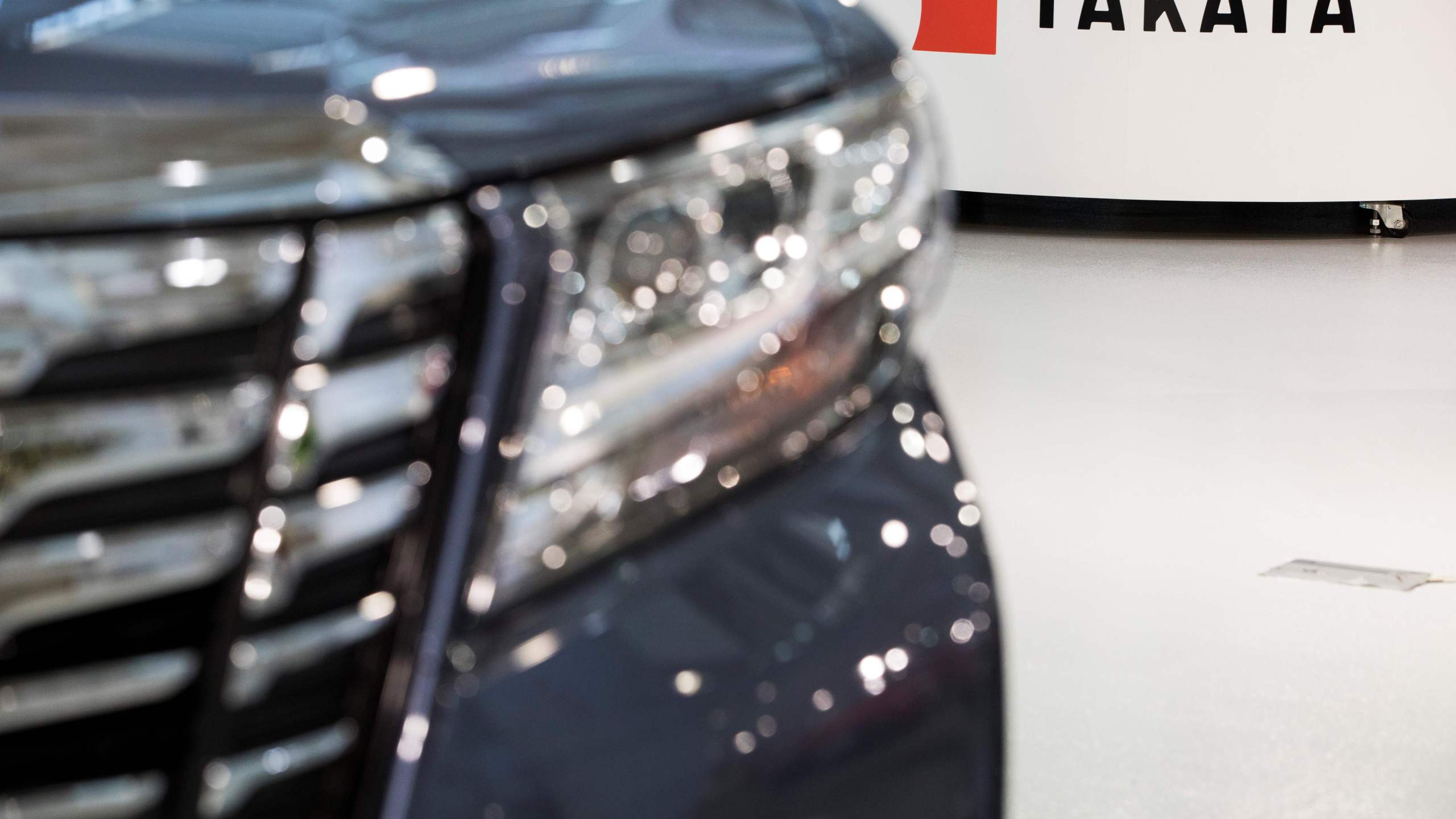 Logo of the Japanese auto parts maker Takata is seen next to a car at a showroom in Tokyo on June 23, 2017.(Credit: BEHROUZ MEHRI/AFP via Getty Images)