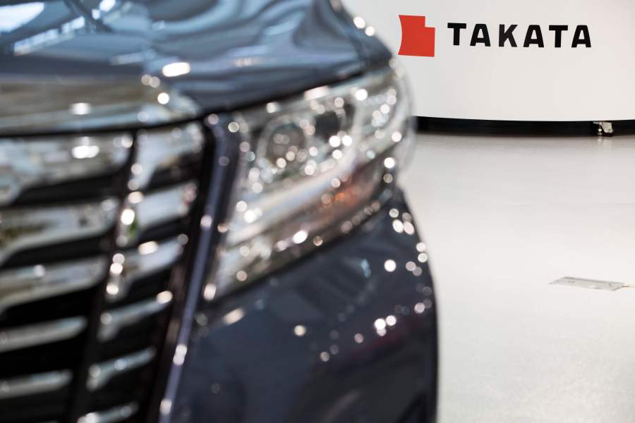 Logo of the Japanese auto parts maker Takata is seen next to a car at a showroom in Tokyo on June 23, 2017.(Credit: BEHROUZ MEHRI/AFP via Getty Images)