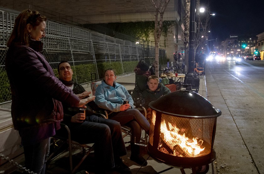 Denise Koehnlein of Phoenix, left, stays warm by the fire while chatting with Mark Breiling, Quisha Ryan and Christian Ryan as they camp and wait for the 2020 Rose Parade on Dec. 31, 2019. (Credit: Gina Ferazzi/ Los Angeles Times)