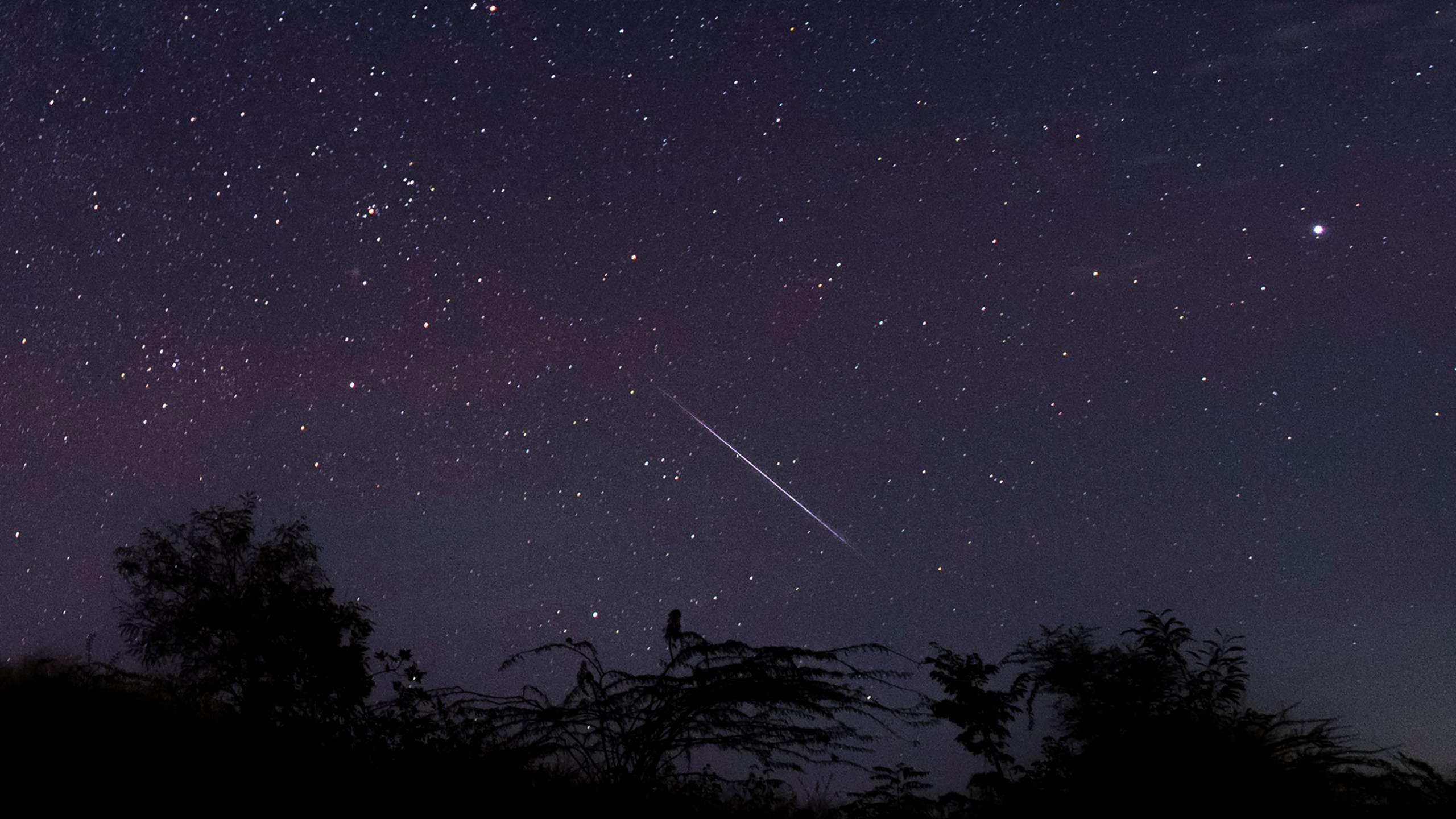 This photo taken late December 14, 2018 with a long time exposure shows a meteor streaking through the night sky over Myanmar during the Geminid meteor shower seen from Wundwin township near Mandalay city. (Credit: YE AUNG THU/AFP via Getty Images)