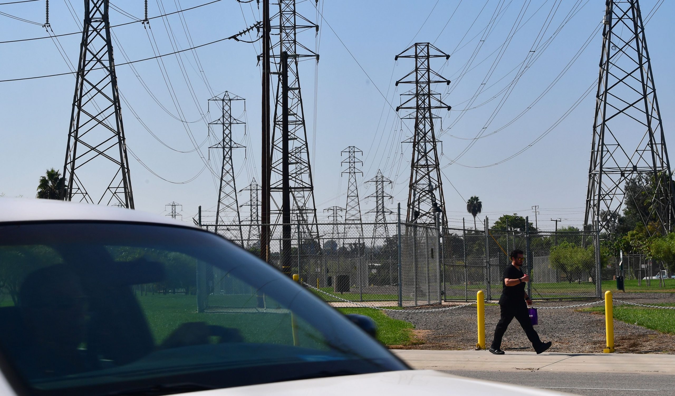 A pedestrian and motorist pass a row of power lines in Rosemead on Oct. 9, 2019. (Frederic J. Brown / AFP / Getty Images)