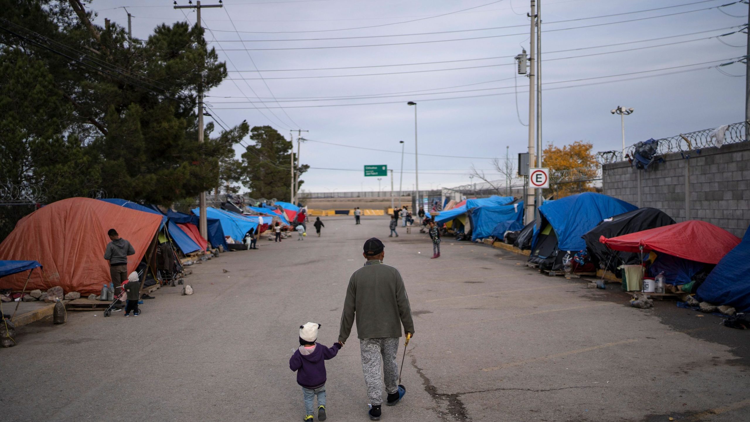 A man walks with his daughter at an asylum seekers camp near the Zaragoza bridge in Ciudad Juarez, Mexico, on Dec. 11, 2019. (Paul Ratje / AFP / Getty Images)