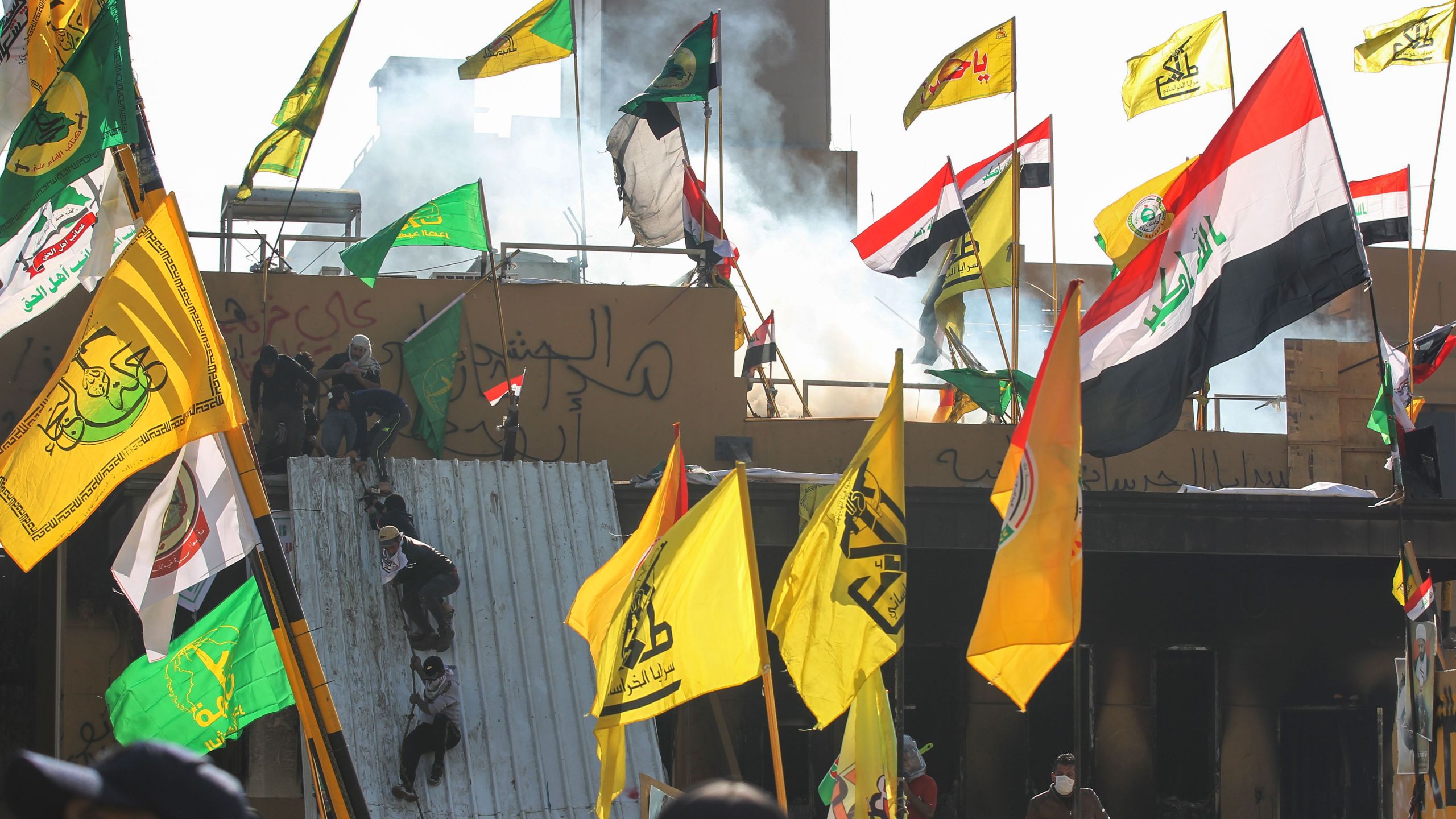 Supporters and members of the Hashed al-Shaabi paramilitary force try to scale a wall of the U.S. embassy in the Iraqi capital Baghdad on January 1, 2020.(Credit: Ahmad Al-Rubaye/AFP via Getty Images)