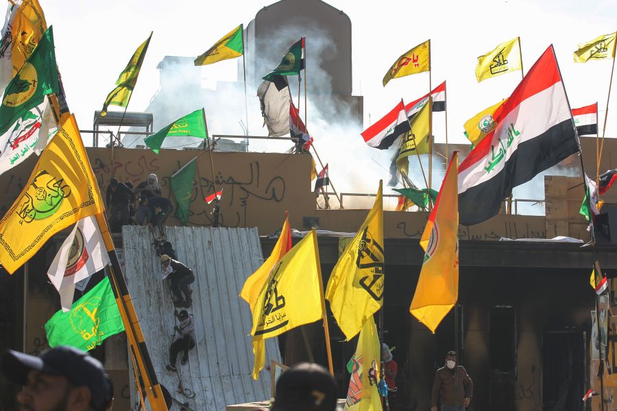 Supporters and members of the Hashed al-Shaabi paramilitary force try to scale a wall of the U.S. embassy in the Iraqi capital Baghdad on January 1, 2020.(Credit: Ahmad Al-Rubaye/AFP via Getty Images)