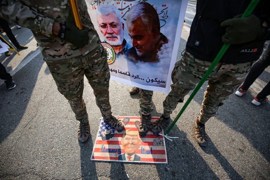 Members of the Hashed al-Shaabi paramilitary force step on a makeshift U.S. flag bearing a caricature of Donald Trump during the funeral procession of Abu Mahdi al-Muhandis, Qassem Soleimani and eight others in the capital Baghdad's district of al-Jadriya, near the high-security Green Zone, on Jan. 4, 2020. (Credit: AHMAD AL-RUBAYE/AFP via Getty Images)