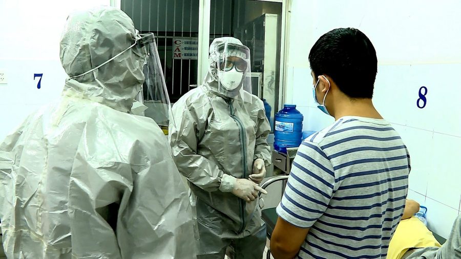 Medical personnel wearing protectice suits interact with two patients (R on bed and standing) tested positive to the coronavirus in an isolation room at Cho Ray hospital in Ho Chi Minh City on January 23, 2020. (Credit: STR/Vietnam News Agency/AFP via Getty Images)