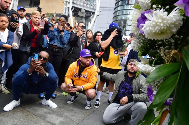 People gather around a makeshift memorial for former NBA star Kobe Bryant in front of Staples Center in Los Angeles on Jan. 26, 2020. (Photo by Frederic J. Brown/AFP via Getty Images)