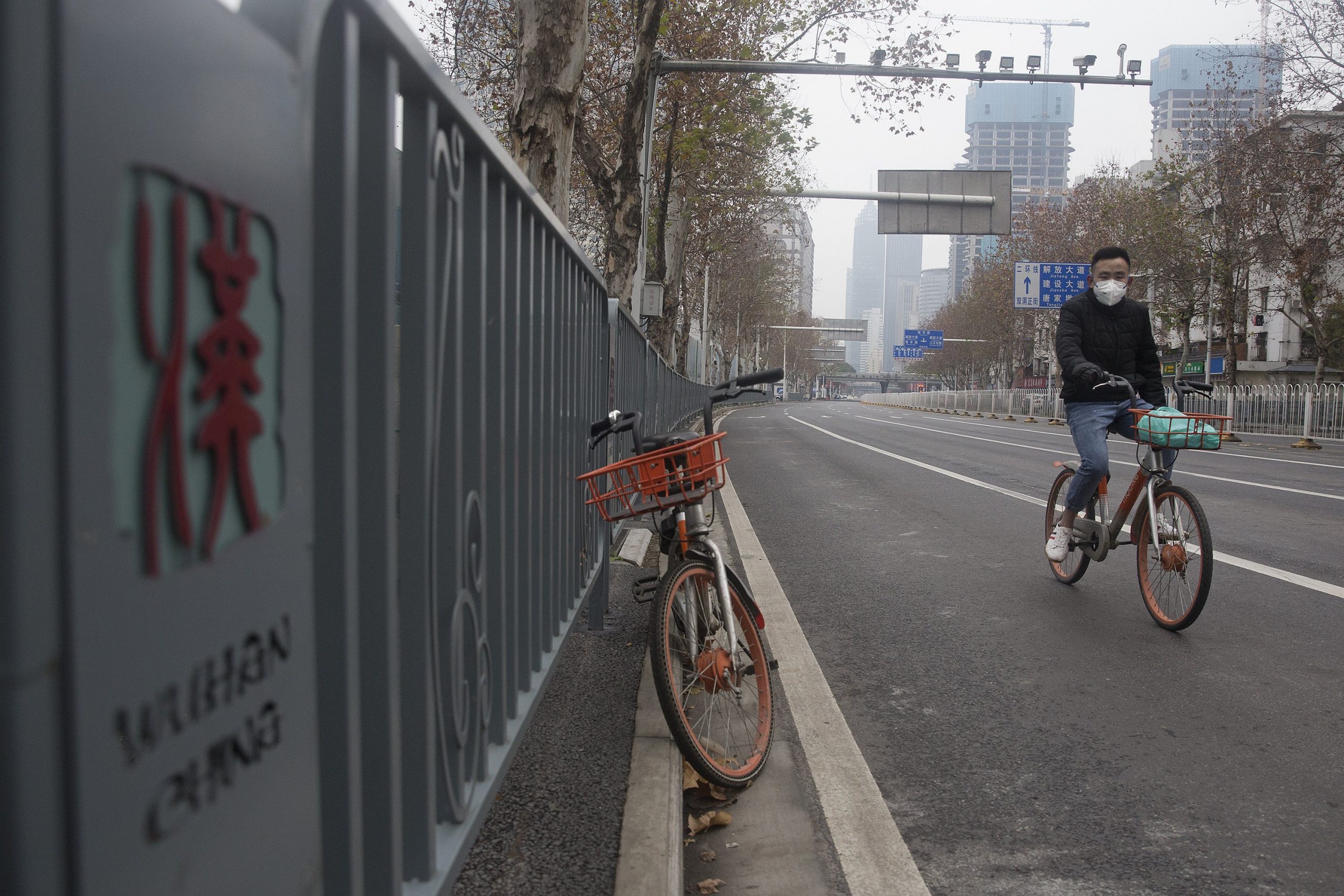 A man wearing a protective mask rides a motorized bike on an empty road on Jan. 27, 2020, in Wuhan, China. (Credit: Getty Images)