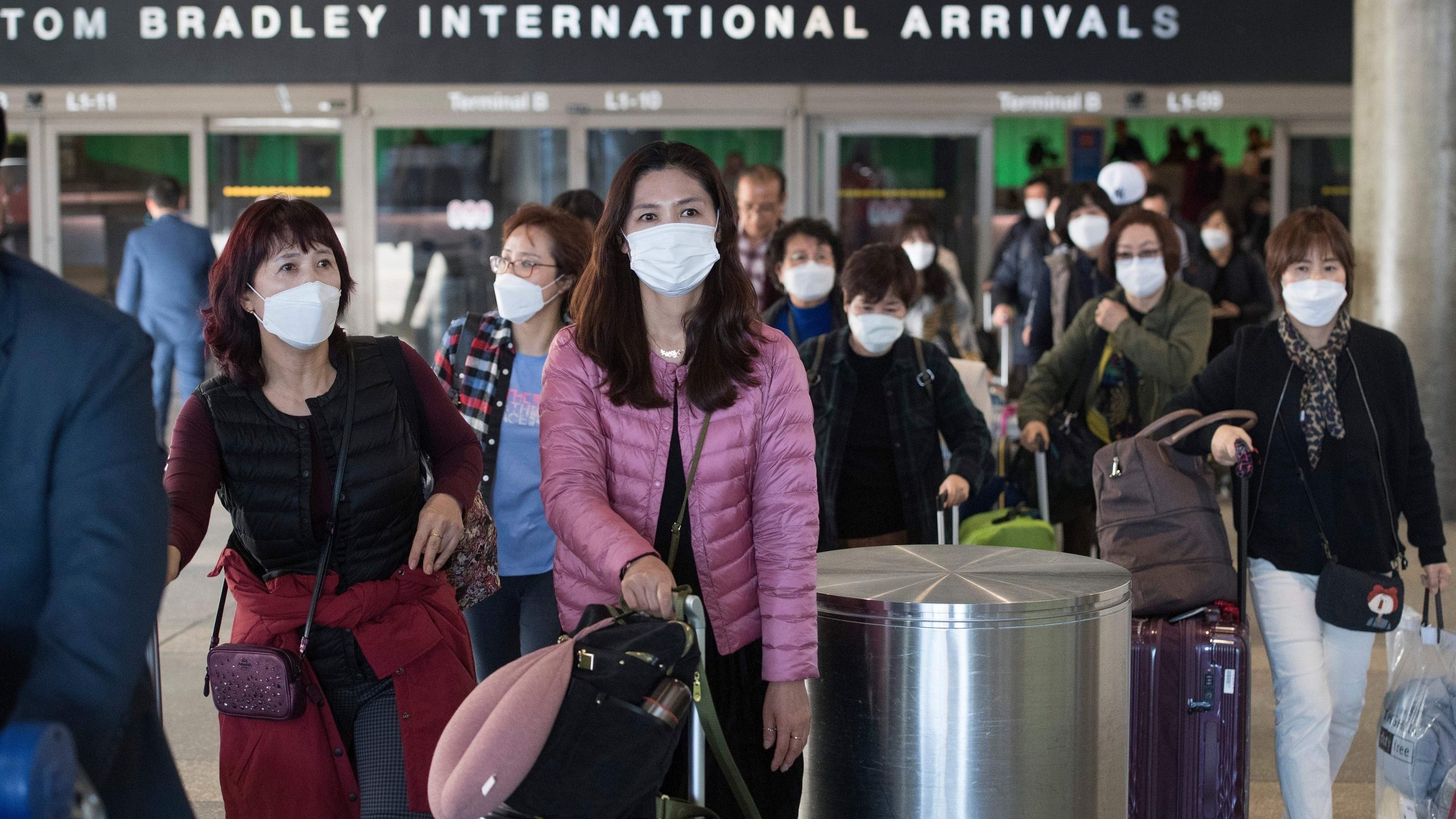 Passengers wear protective masks to protect against the spread of the Coronavirus as they arrive on a flight at Los Angeles International Airport in Los Angeles on Jan. 29, 2020. (Credit: MARK RALSTON/AFP via Getty Images)