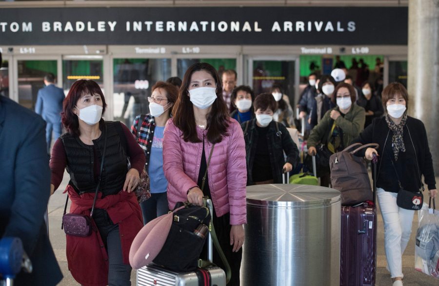 Passengers wear protective masks to protect against the spread of the Coronavirus as they arrive on a flight at Los Angeles International Airport in Los Angeles on Jan. 29, 2020. (Credit: MARK RALSTON/AFP via Getty Images)