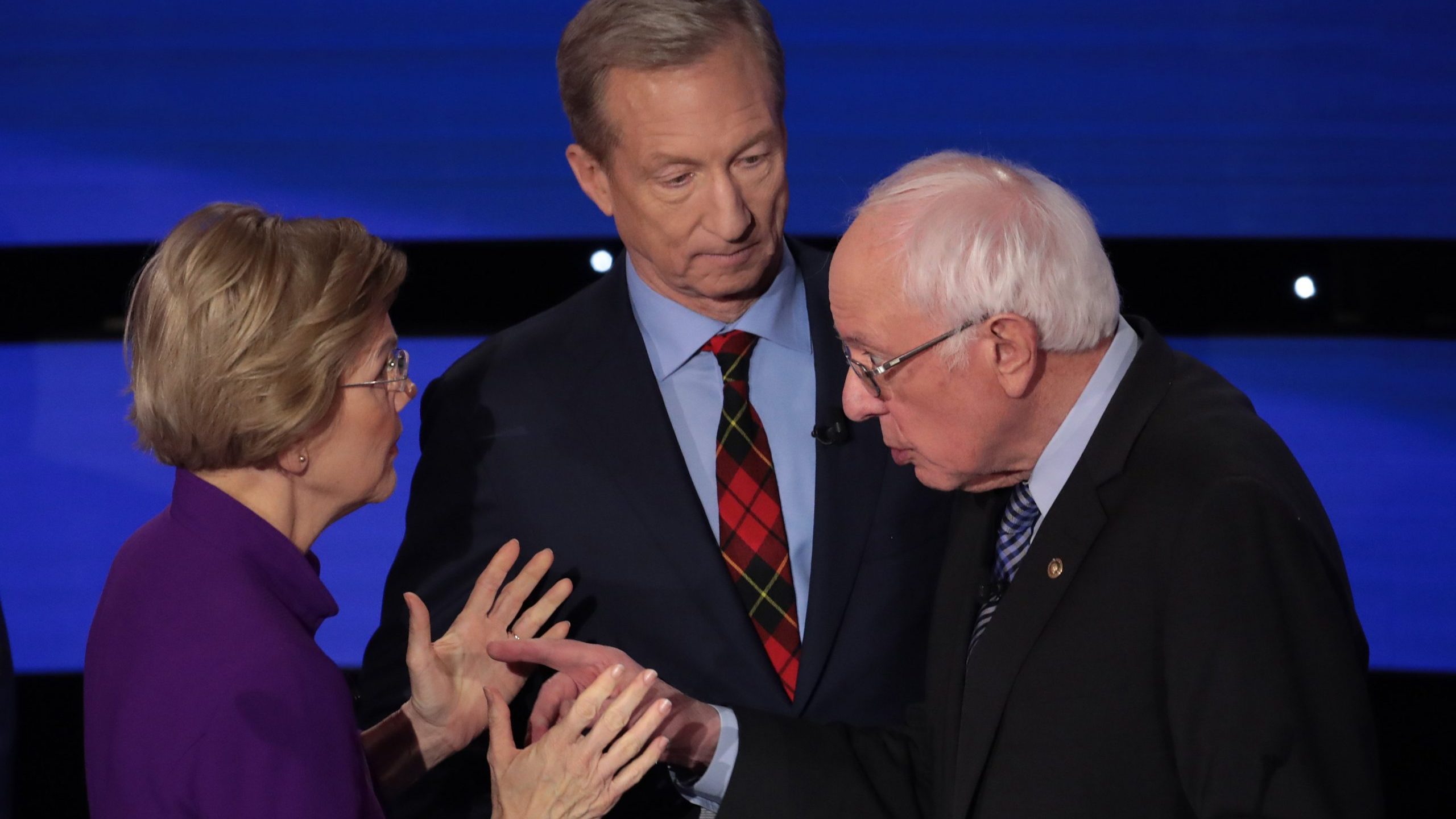 Sen. Elizabeth Warren (D-MA) and Sen. Bernie Sanders (I-VT) speak as Tom Steyer looks on after the Democratic presidential primary debate on Jan. 14, 2020 in Des Moines, Iowa. (Credit: Scott Olson/Getty Images)