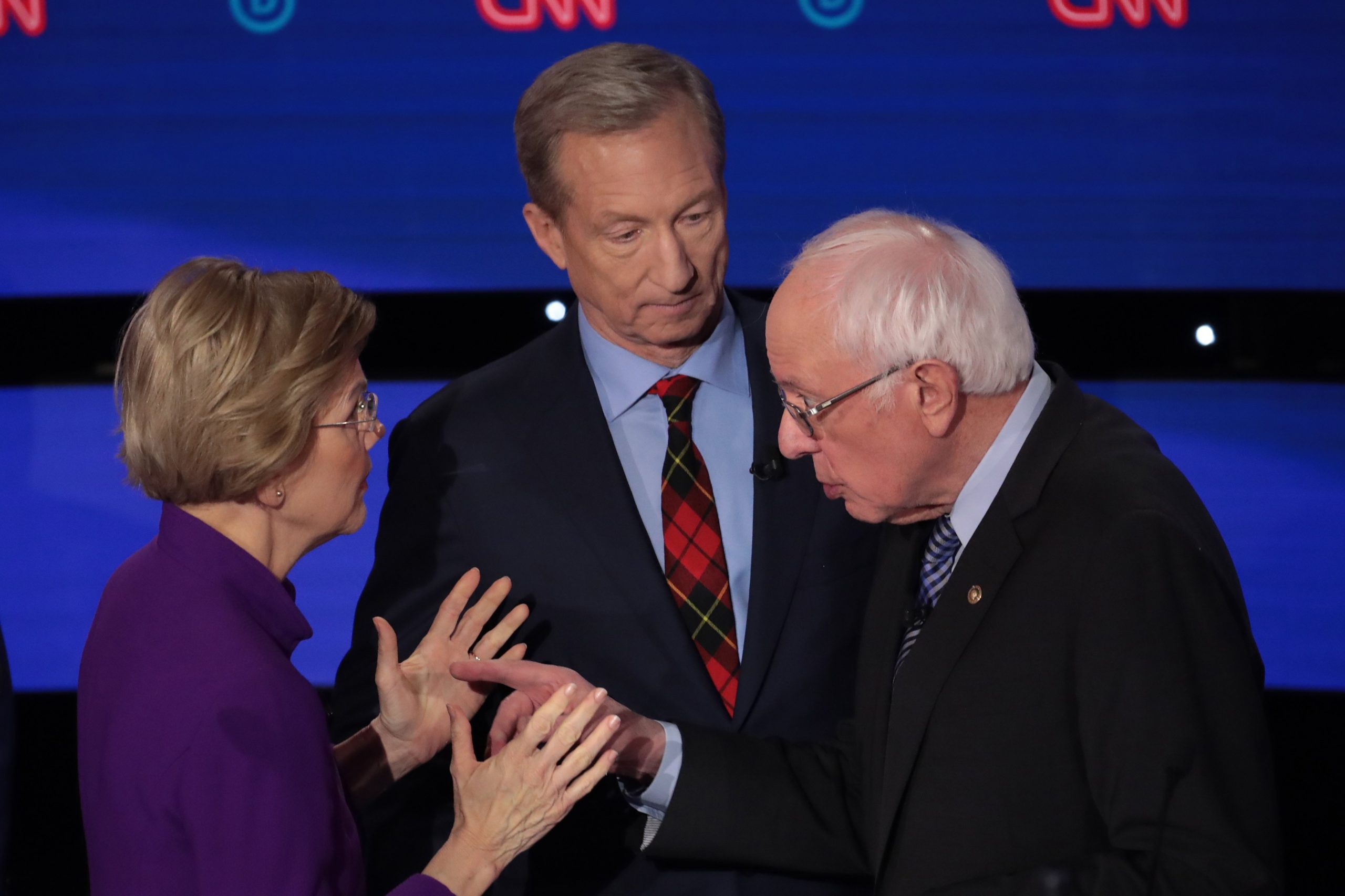 Sen. Elizabeth Warren (D-MA) and Sen. Bernie Sanders (I-VT) speak as Tom Steyer looks on after the Democratic presidential primary debate on Jan. 14, 2020 in Des Moines, Iowa. (Credit: Scott Olson/Getty Images)