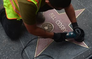 A worker cleans actor Bill Cosby's star on the Hollywood Walk of Fame on Dec. 5, 2014, after it was reportedly vandalized the night before with the word "rapist." (Credit: Frederic J. Brown / AFP / Getty Images)