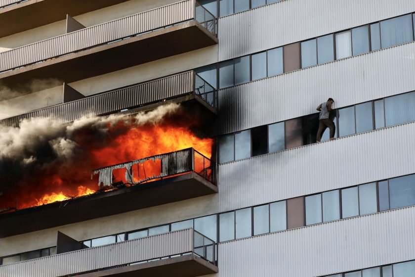 A man is seen clinging to the window of a Brentwood-area high-rise during a fire on Jan. 29, 2020. (Credit: Al Seib / Los Angeles Times)