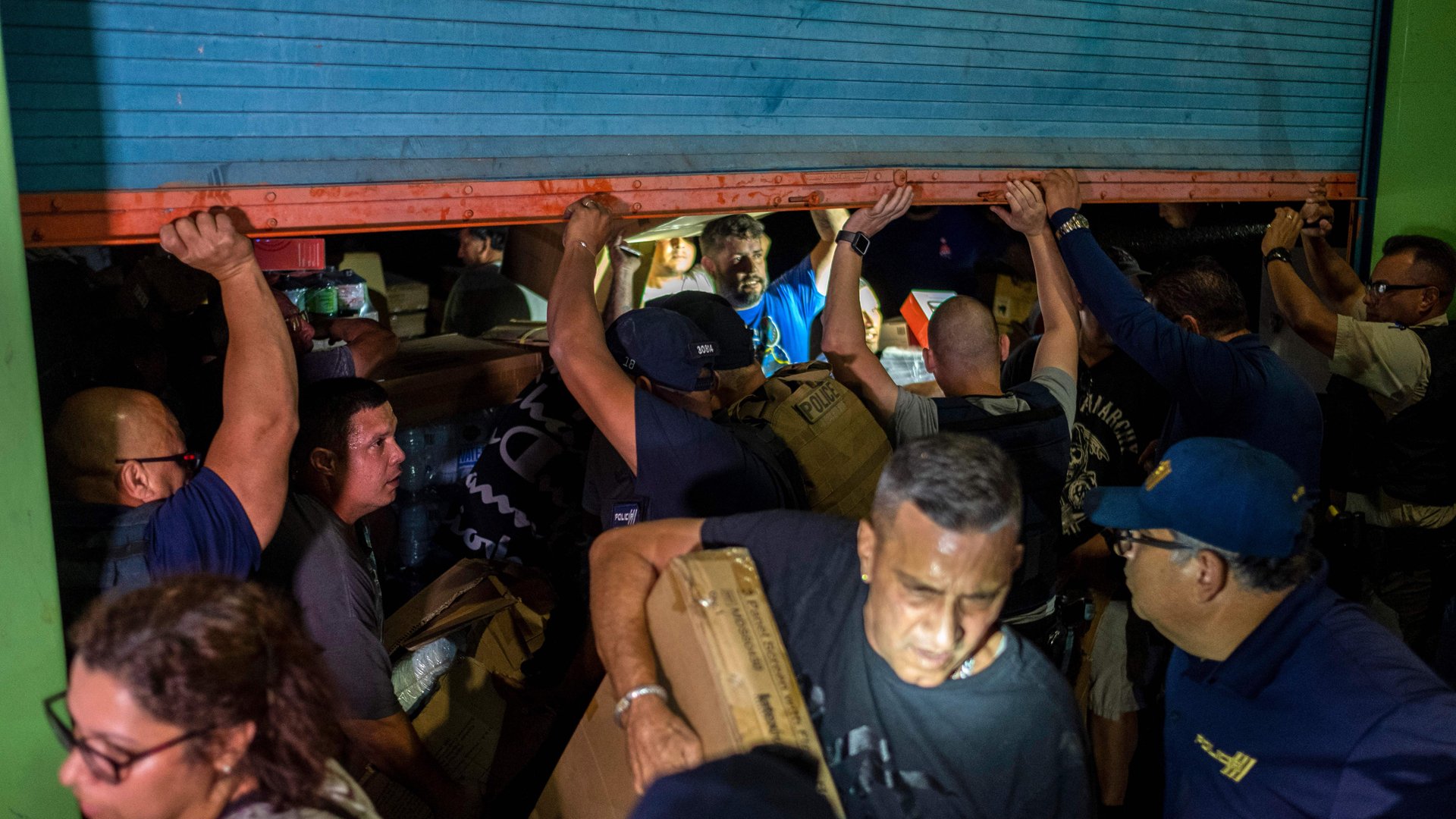 Police arrive as people break into a warehouse filled with supplies, believed to have been from when Hurricane Maria struck the island in 2017 in Ponce, Puerto Rico on January 18, 2020, after a powerful earthquake hit the island. (Credit: Ricardo Arduengo/AFP’Getty Images)